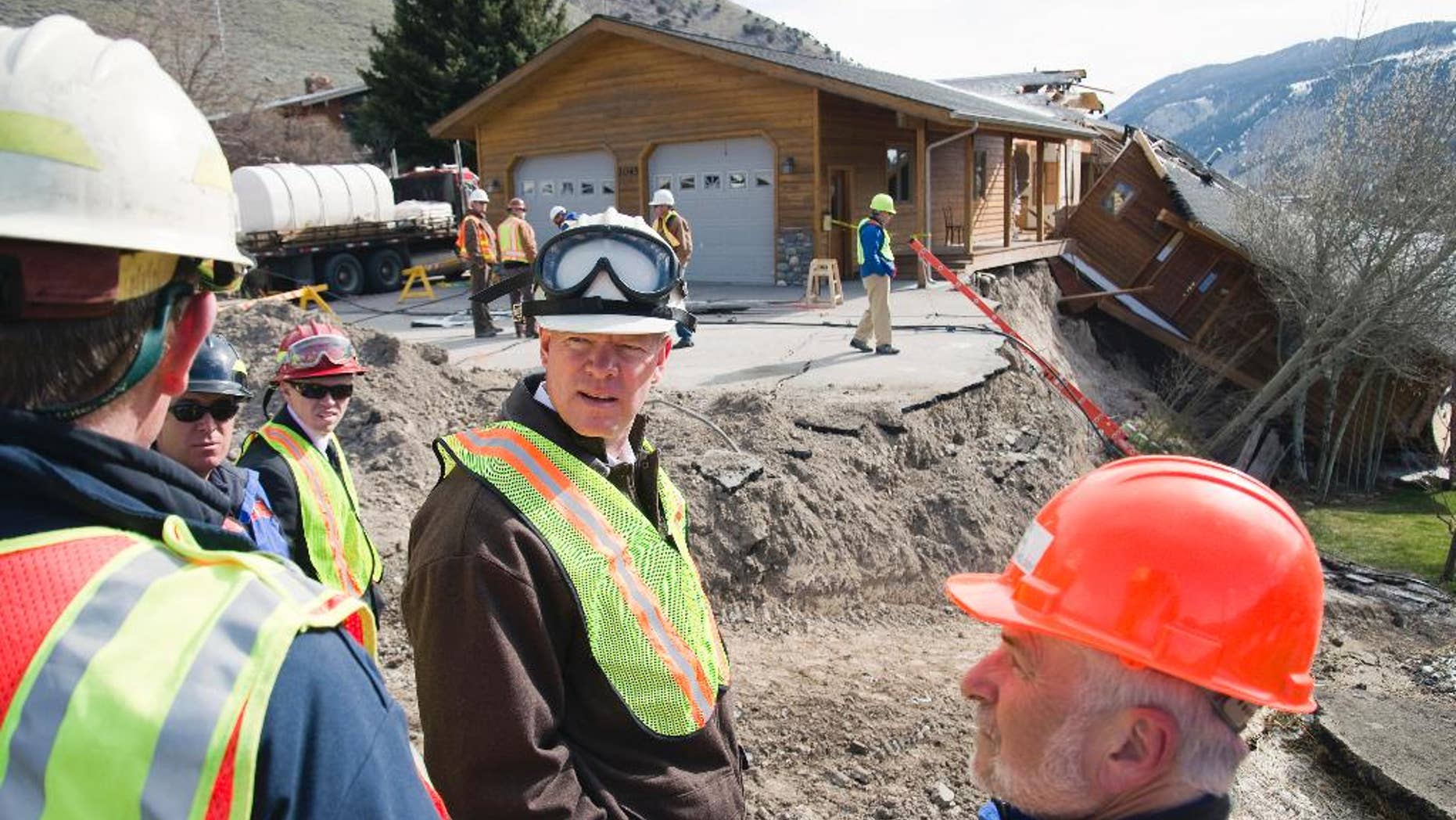 Wyoming Gov. Matt Mead, center, listens to Jackson town officials during a tour the East Gros Ventre Butte landslide Monday, April 28, 2014, in Jackson, Wyo. Mead says after touring a slow-moving landslide he wants to help local officials defray the cost of the disaster. Efforts to slow the slide by hauling in tons of dirt and rock appear to be working. Ground movement has slowed to just a tenth of an inch per day — much less than a surge April 17 and 18 that sheared one house in two. (AP Photo/Jackson Hole News&Guide, Bradly J. Boner)