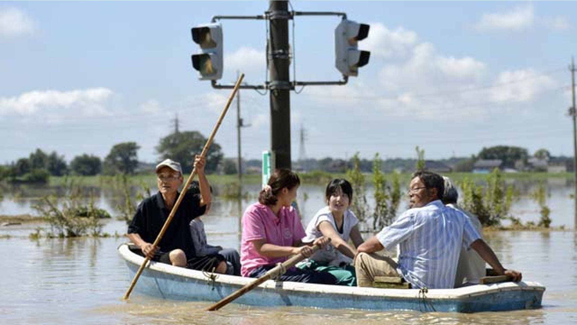 Sept. 11, 2015: Residents paddle a boat past a traffic light in the flooded road in Joso, Ibaraki prefecture, northeast of Tokyo. (Kyodo News via AP)