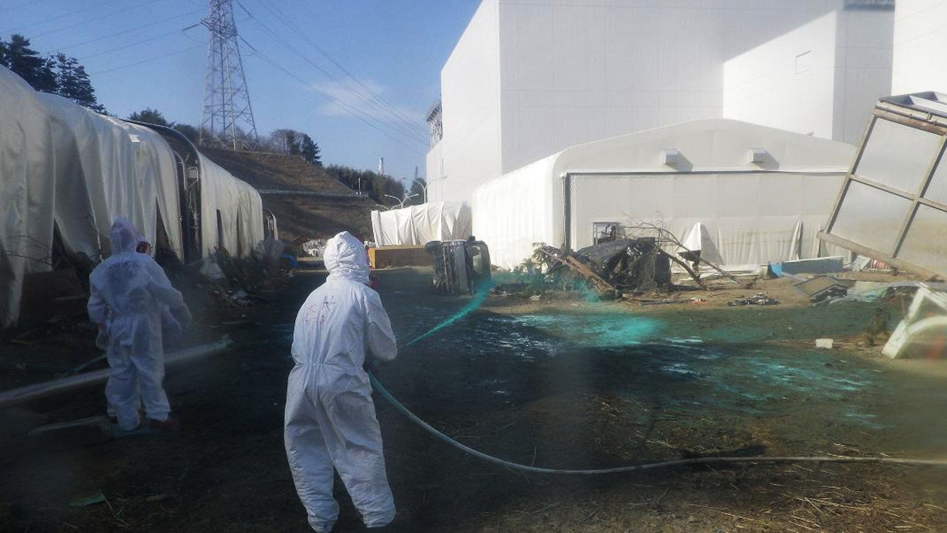 April 1: Workers for the company experimentally spray adhesive synthetic resin over the ground at the Fukushima Dai-ichi nuclear power plant in Okumamachi, northeastern Japan. TEPCO expects the resin spraying to prevent dust exposed to radiation materials from spreading out of the premises. (AP/TEPCO)