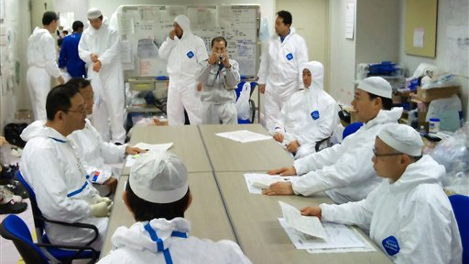 April 9: In this photo released by Nuclear and Industrial Safety Agency via Kyodo News, Japanese Trade Minister Banri Kaieda, second right, in protective suit listens to employees of Tokyo Electric Power Co. inside the waste processing building of the Fukushima Dai-ichi nuclear power plant during his one-day trip to the tsunami-crippled complex in Okuma town, Fukushima Prefecture. (AP/Nuclear and Industrial Safety Agency)