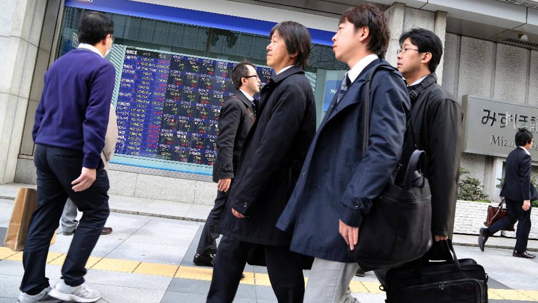 People walk by an electronic stock board of a securities firm in Tokyo, Friday, March 13, 2015. Asian stock markets mostly rose Friday after weak U.S. retail sales alleviated jitters about the Federal Reserve's timetable for raising interest rates. Japan's Nikkei 225 rose 1.4 percent to 19,254.25. (AP Photo/Koji Sasahara)