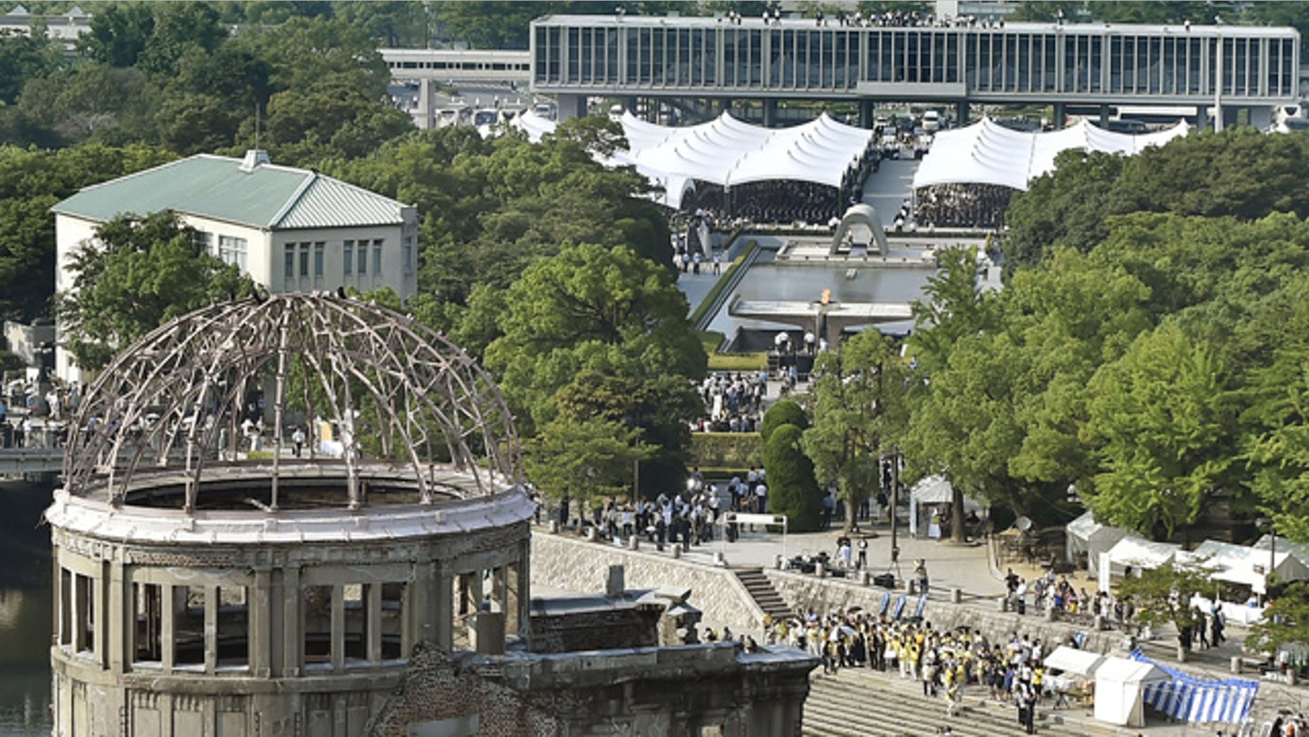 August 6, 2015: The Atomic Bomb Dome stands in front as a ceremony to mark the 70th anniversary of the atomic bombing of Hiroshima is held at the Hiroshima Peace Memorial Park, seen in the center, in Hiroshima, Japan. (Kyodo Photo via AP)