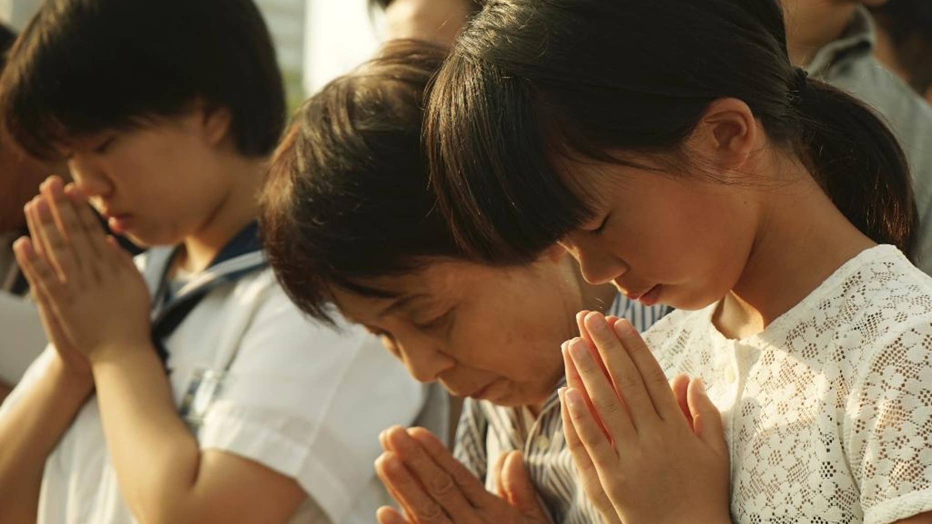 Visitors pray for the atomic bomb victims in front of the cenotaph at the Hiroshima Peace Memorial Park in Hiroshima, western Japan, Thursday, Aug. 6, 2015. Japan marked the 70th anniversary of the atomic bombing on Hiroshima. (AP Photo/Koji Ueda)