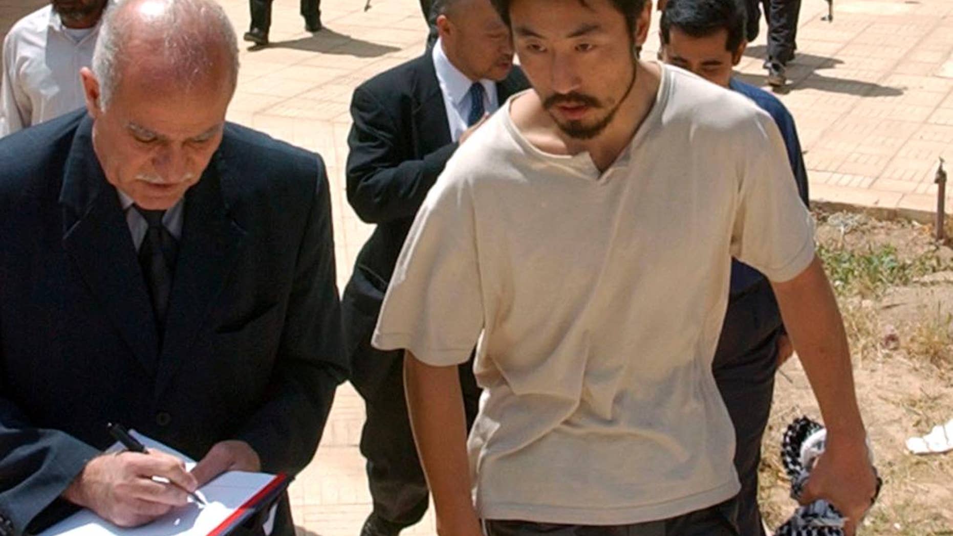 FILE - In this April 17, 2004 file photo, Japanese freelance journalist Jumpei Yasuda, right, is escorted after being released at Umm Al-Qura mosque in Baghdad, Iraq. Worries are growing about the whereabouts of the freelance Japanese journalist, last heard from late June, 2015, in Syria. It is not known why Yasuda, who has been reporting on the Middle East since 2002, has not been in contact or if he has been taken captive in the war-torn nation. (AP Photo/Muhammed Muheisen, File)