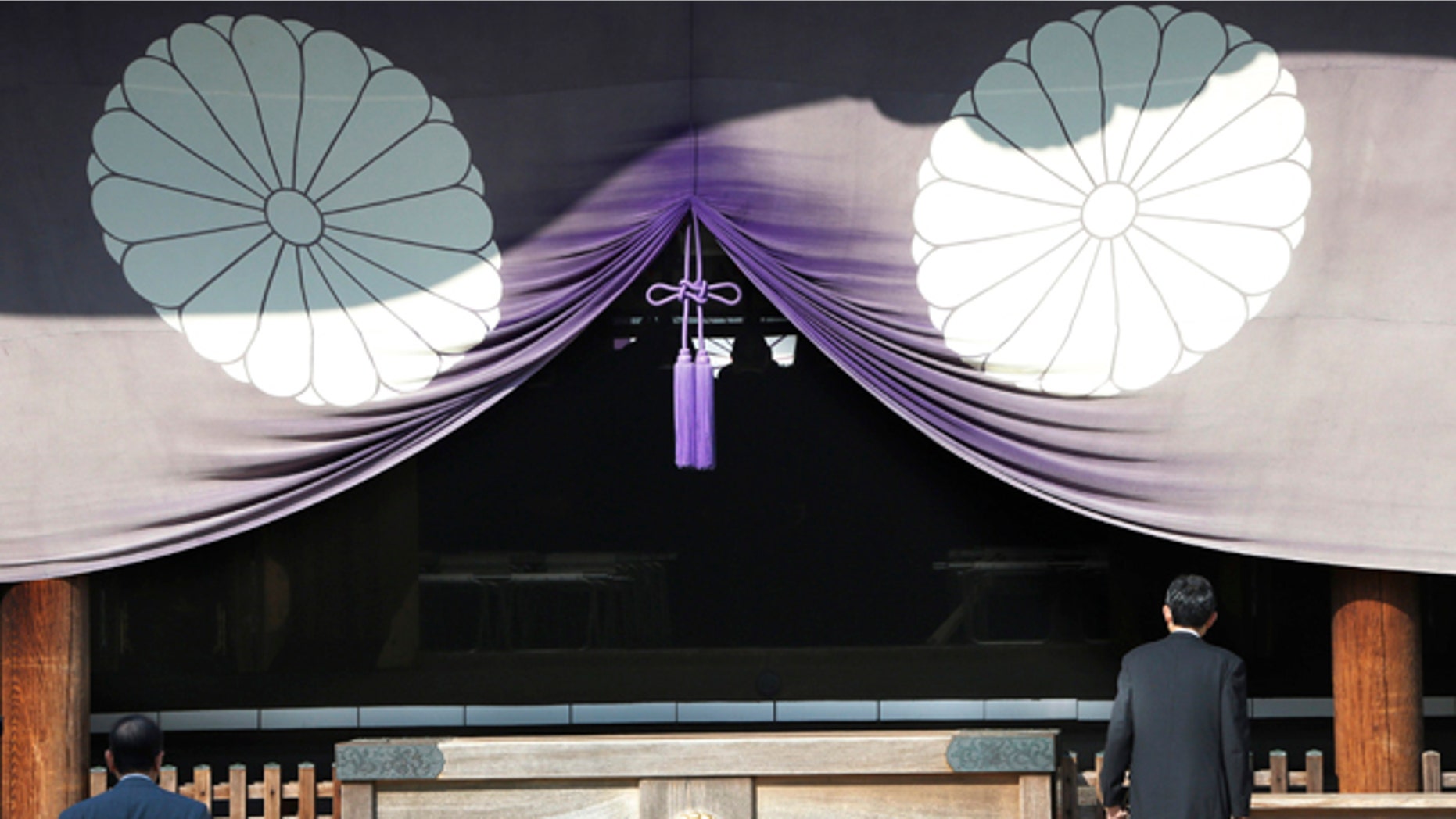 FILE - In this April 23, 2013 file photo, a group of Japanese lawmakers, seen silhouetted in the middle of the photo, offer prayers at the Yasukuni Shrine, which honors Japan's war dead, including World War II leaders convicted of war crimes, in Tokyo during an annual spring festival. (AP Photo/Koji Sasahara, File)