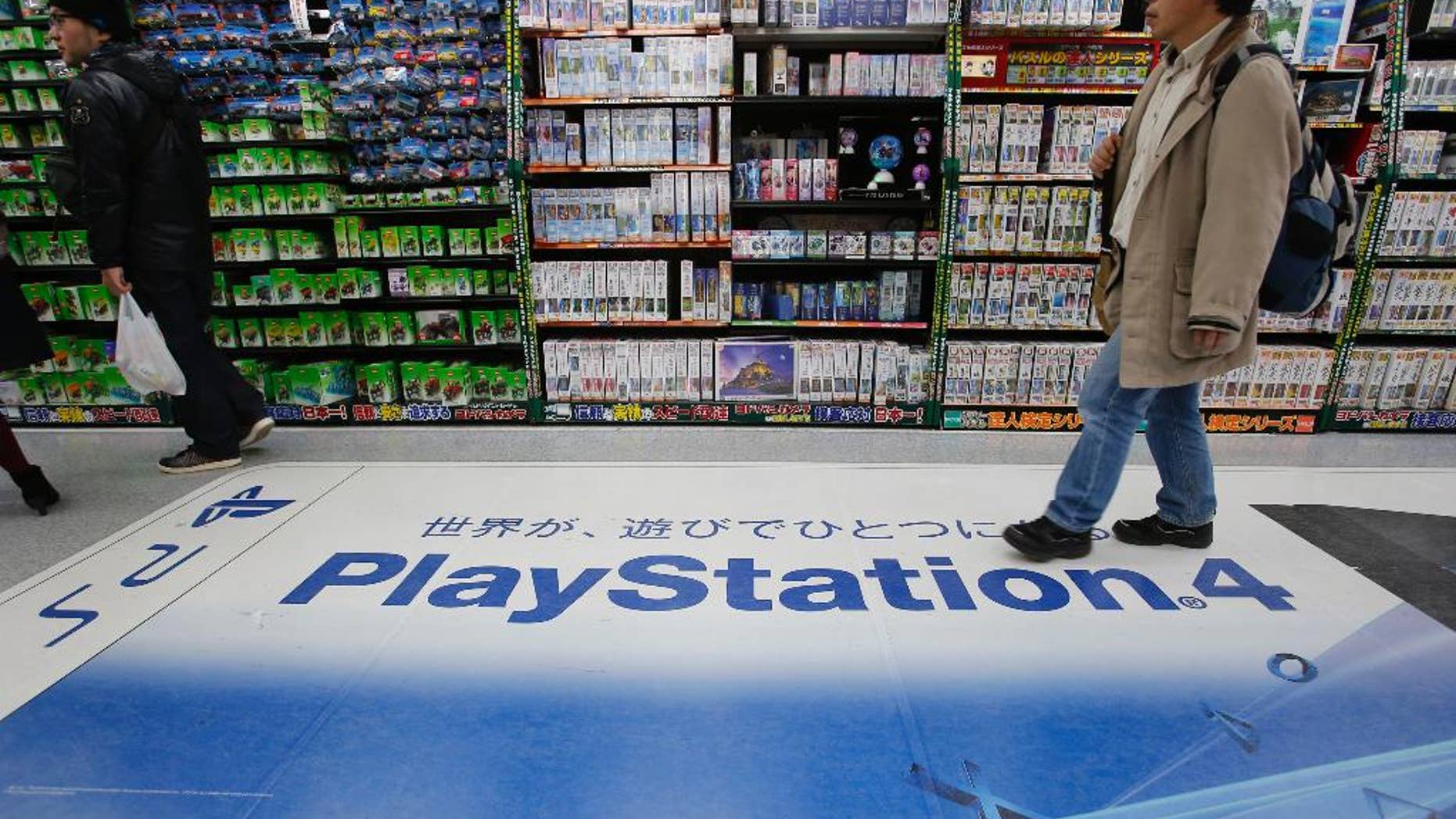 In this Thursday, Dec. 25, 2014 photo, a shopper walks on the logo of Sony's PlayStation 4 at an electronics store in Tokyo. Sony's online PlayStation store and Microsoft's Xbox site suffered disruptions to users on Christmas Day in the latest possible cyber-attacks on the companies. The PlayStation Store Twitter feed said Friday, Dec. 26 that some users were having trouble logging into its network. It said engineers were investigating. (AP Photo/Shizuo Kambayashi)