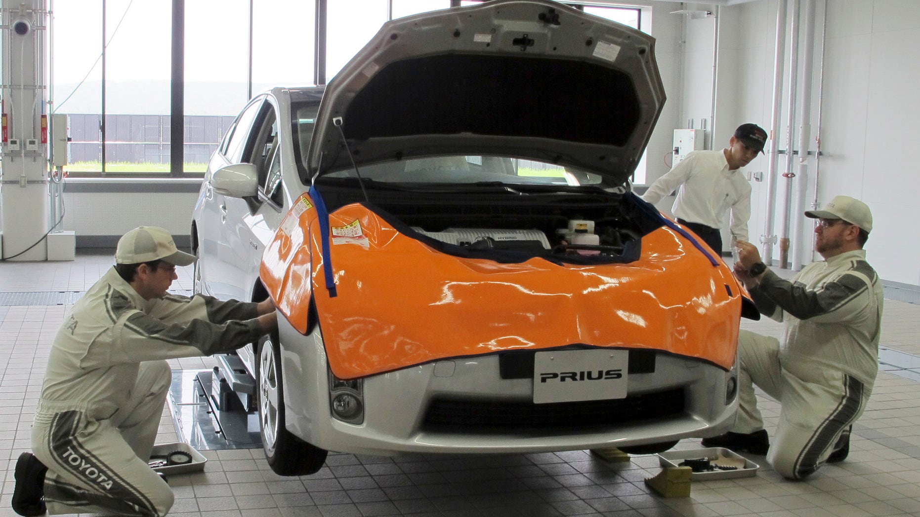 Mechanics work on Prius at a newly completed Toyota's service center in Tajimi, central Japan, Monday, July 22, 2013. Toyota is opening a training facility for mechanics complete with a test course that simulates 13 driving conditions including cobblestones and bumpy roads as part of the automaker's efforts to avoid a repeat of its recall fiasco. (AP Photo/Yuri Kageyama)