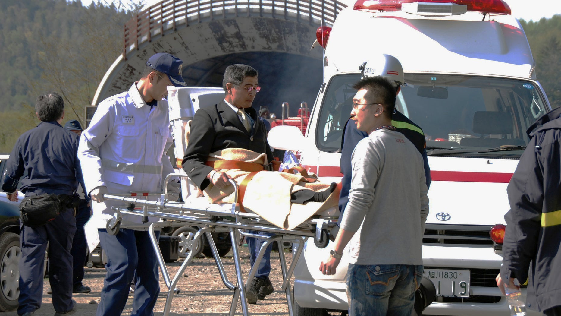 An emergency member carries an injured person into an ambulance after Japan Railway's express train made an emergency stop in a tunnel, seen in the background, in Shimukappu village, northern Japan, Saturday, May 28, 2011. The operator of the train that derailed and caught fire Friday night in northern Japan came under criticism Saturday for acting too slowly to evacuate the passengers.