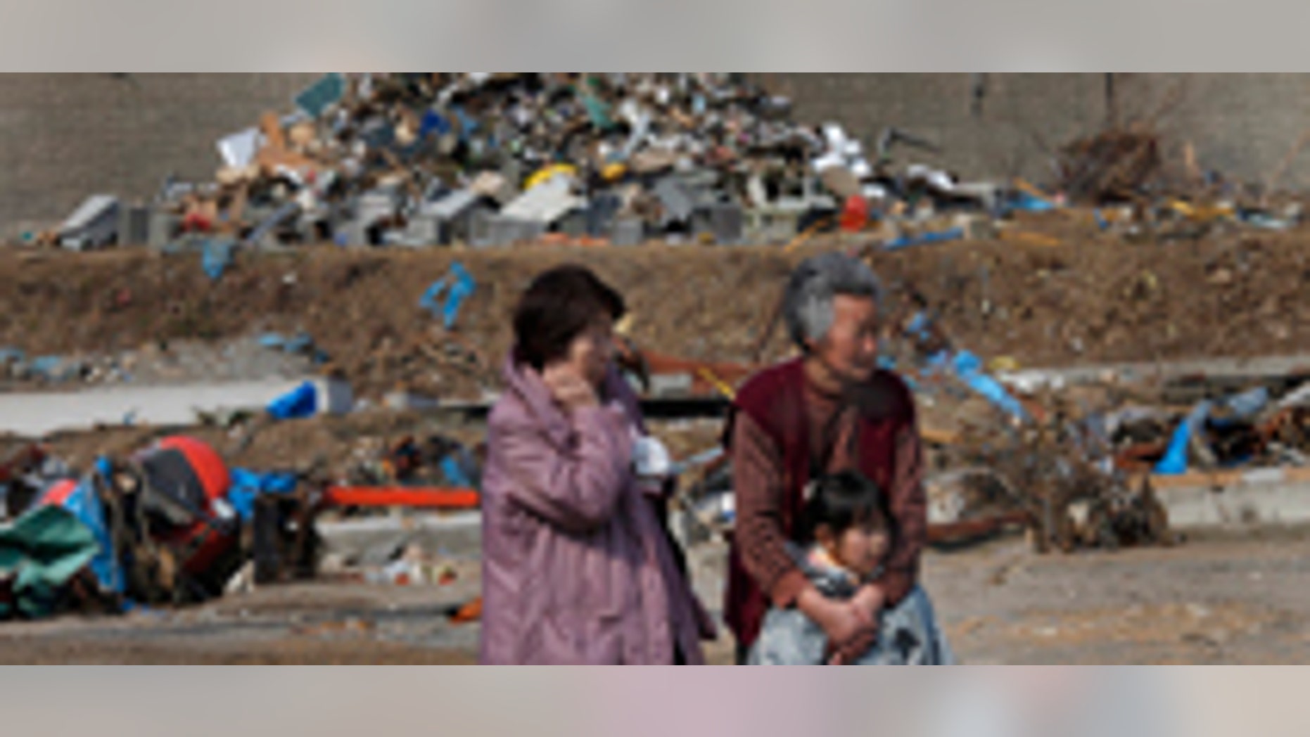 March 31: Survivors watch workers finding victims at the tsunami-destroyed town of Yamada, Iwate Prefecture, northern Japan.