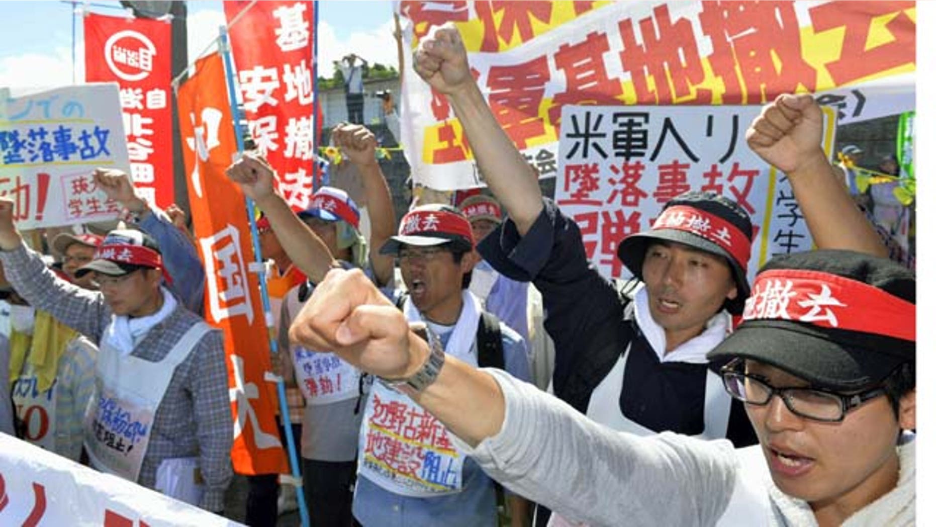 August 6, 2013: Protesters chant slogans against Monday's accident of a U.S. military helicopter crash and planned additional deployment of Osprey transport aircraft in front of a gate to U.S. Marine Corps Futenma Air Station in Ginowan, Okinawa, southwestern Japan. (AP Photo)