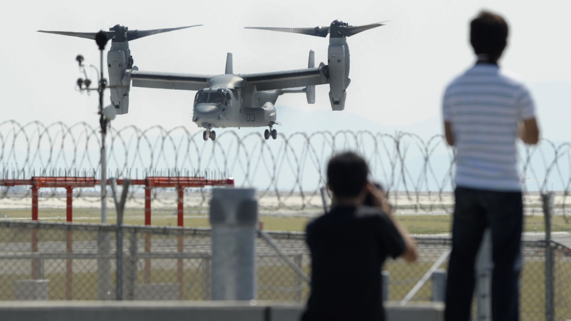 Photographers stand as an MV-22 Osprey aircraft takes off from Iwakuni Air Base, Yamaguchi prefecture, southern Japan, Friday, Sept. 21, 2012. The U.S. Marines conducted their first test flights of the MV-22 Osprey aircraft in Japan after months of protests there over safety concerns. (AP Photo/Kyodo News) JAPAN OUT, MANDATORY CREDIT, NO LICENSING IN CHINA, HONG KONG, JAPAN, SOUTH KOREA AND FRANCE