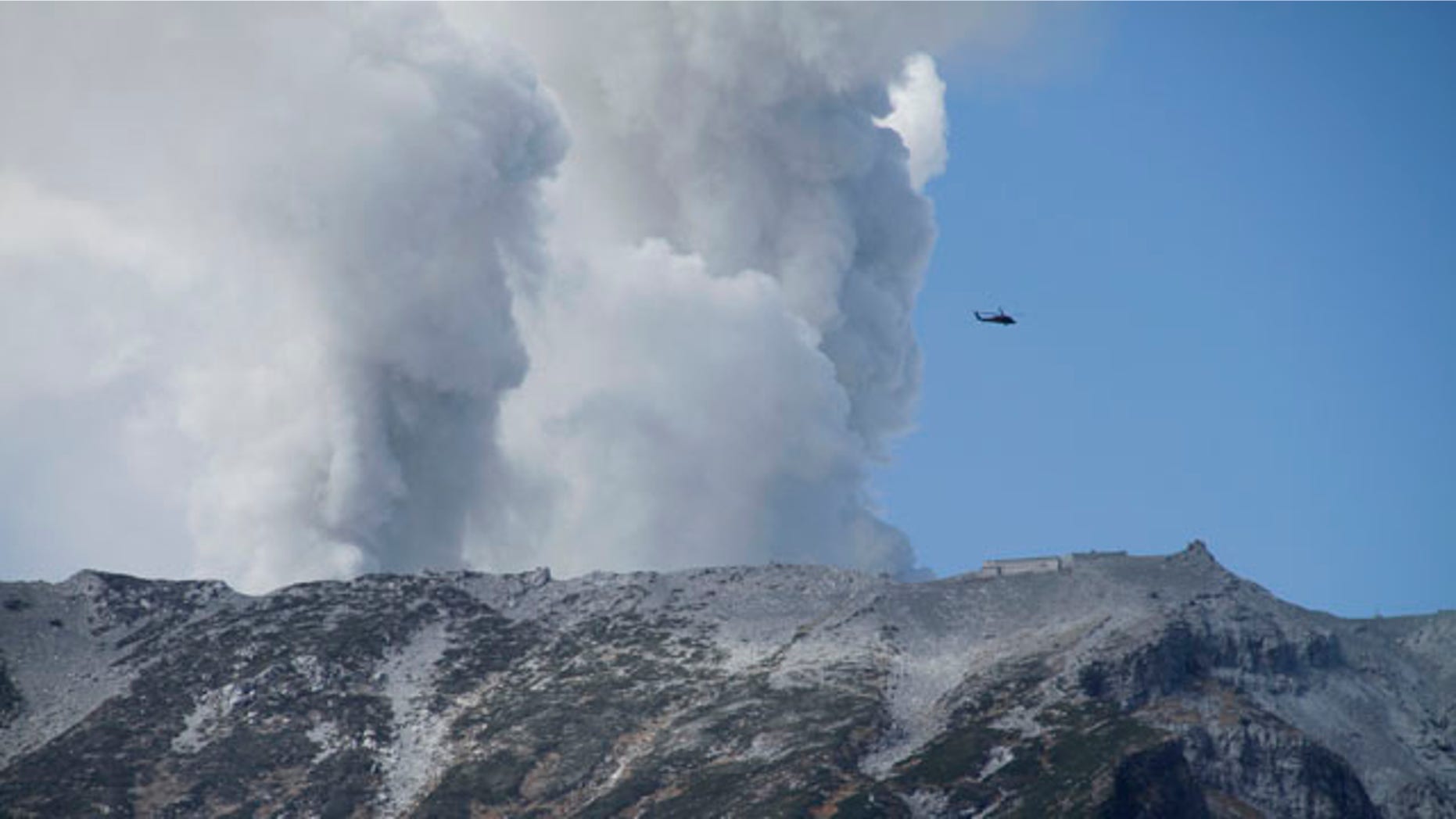 September 28, 2014: A military helicopter, aiding in rescue operations, flies above Mount Ontake as it continues to erupt in Nagano prefecture.