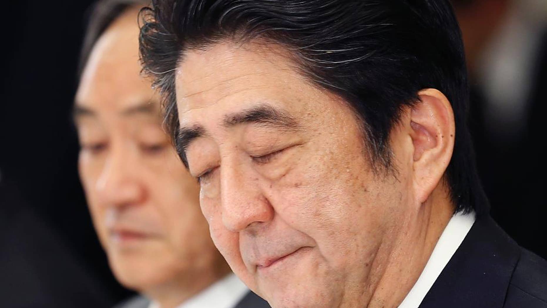 In this Wednesday, Feb. 25, 2015 photo, Japanese Prime Minister Shinzo Abe bites his lips during a meeting with a panel of experts at his official residence in Tokyo. Abe convened the experts to advise him on what to say to mark the 70th anniversary of the end of World War II on Aug. 15. A tug-of-war has emerged between those who want Abe to stick to the apologies made by past prime ministers for Japan's wartime aggression and colonial rule, and those who say such accounts are exaggerated or even fabricated. Abe, known for harboring revisionist views, must strike a balance, as any statement viewed as watering down past apologies would anger China and South Korea and displease the United States too. Behind Abe is government spokesman Chief Cabinet Secretary Yoshihide Suga. (AP Photo/Shizuo Kambayashi)