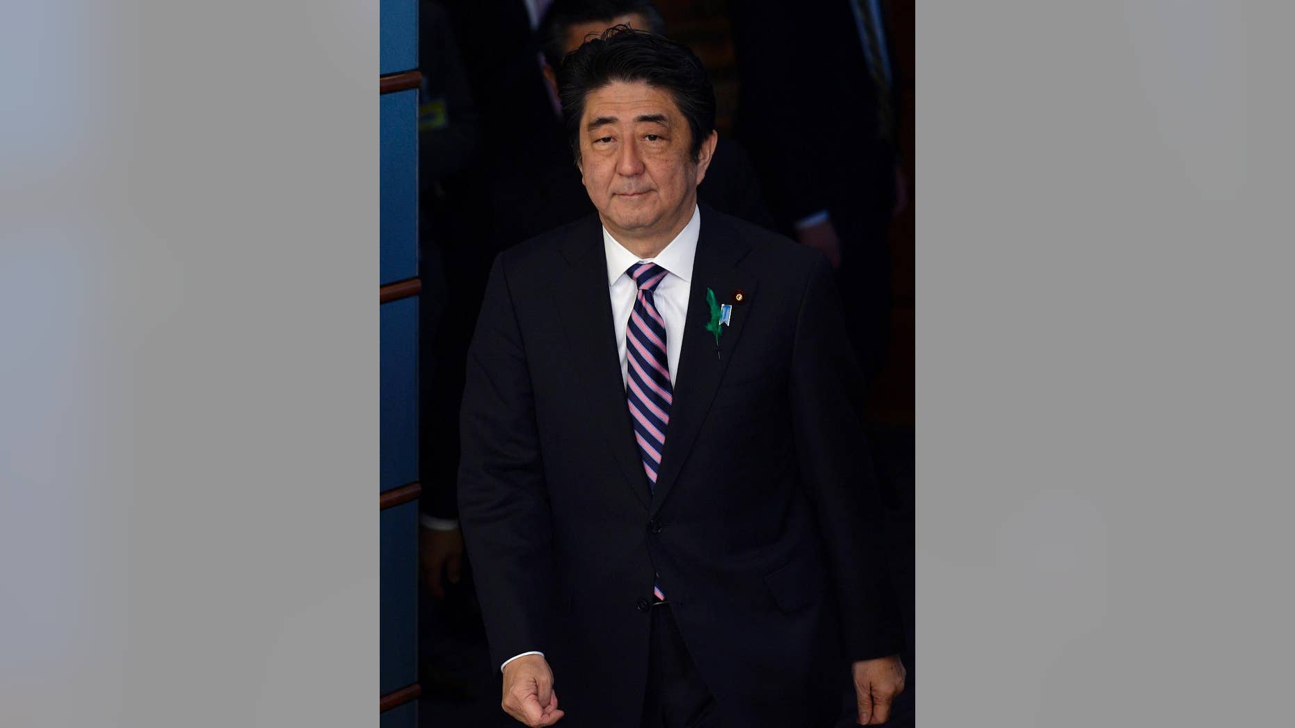 Japanese Prime Minister Shinzo Abe walks on his way to meet a delegation of US representatives at the premier's official residence in Tokyo, Japan, Monday, April 21, 2014. Japan's Prime Minister Abe has sent a religious offering to a Tokyo shrine that honors the dead including executed war criminals, a center of tension with Japan's neighbors. Abe's offering Monday at the Yasukuni Shrine marks the April 21-23 spring festival, one of the shrine's key annual events. But the move suggests he will not visit Yasukuni ahead of President Barack Obama's visit beginning Wednesday. (AP Photo/Franck Robicon, Pool)