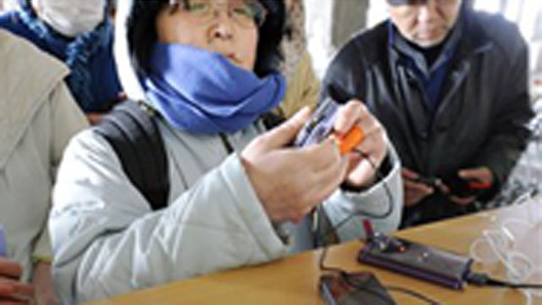 People recharge their cell phones at a shelter for Friday's earthquake and tsunami victims in Ishinomaki, Miyagi Prefecture, northern Japan, Thursday, March 17, 2011.