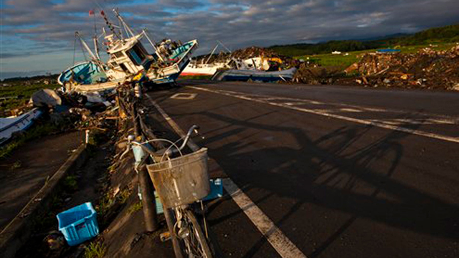 July 24, 2011: In this file photo an abandoned bicycle rests on a road partially blocked by ships that washed ashore in the town of Namie, inside the 12-mile exclusion zone around the Fukushima Dai-ichi nuclear plant, in northeastern Japan.
