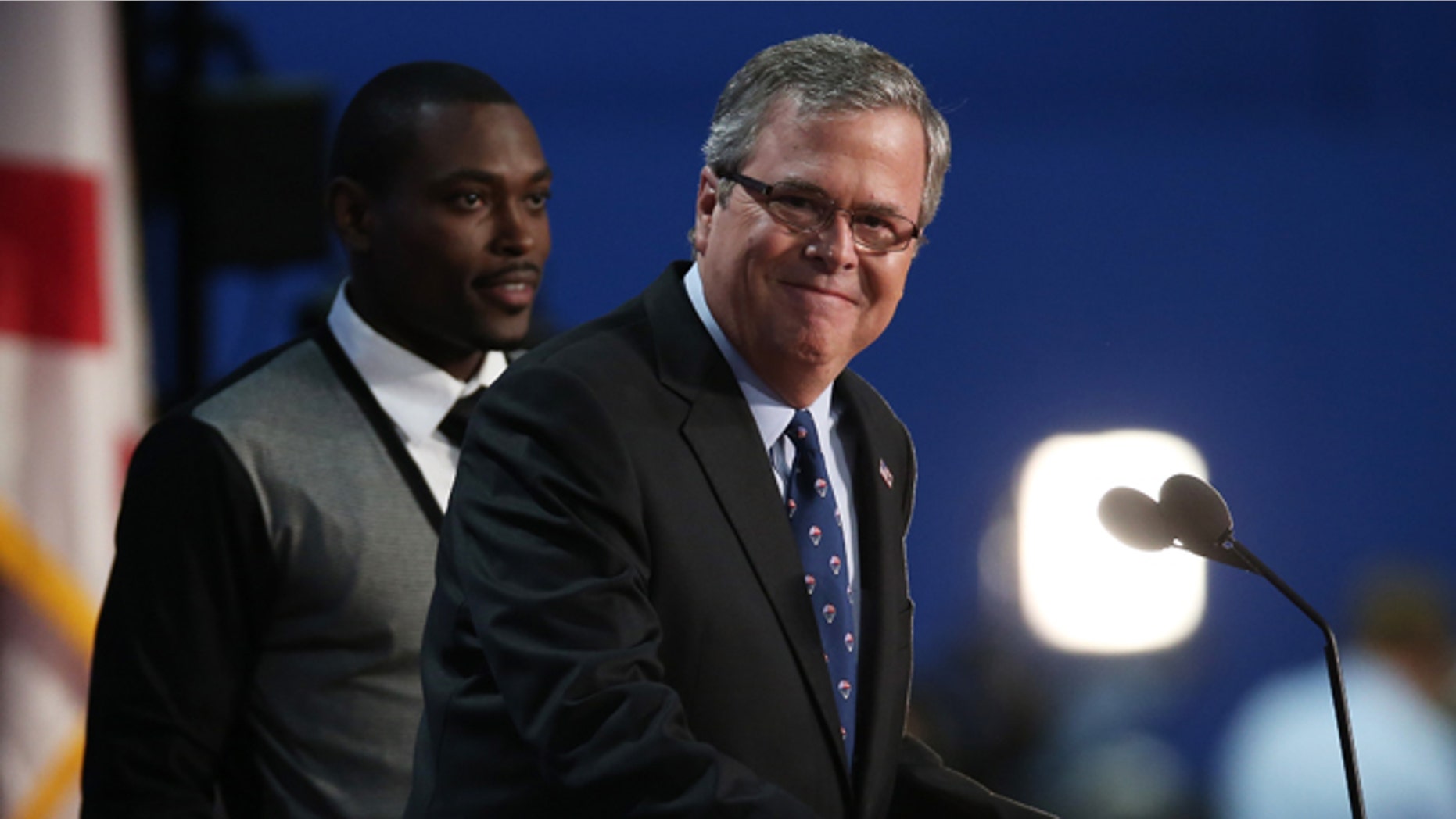 TAMPA, FL - AUGUST 30: Former Florida Gov. Jeb Bush speaks on stage with student Frantz Placide (L) of Miami, FL during the final day of the Republican National Convention at the Tampa Bay Times Forum on August 30, 2012 in Tampa, Florida. Former Massachusetts Gov. Mitt Romney was nominated as the Republican presidential candidate during the RNC which will conclude today. (Photo by Win McNamee/Getty Images)