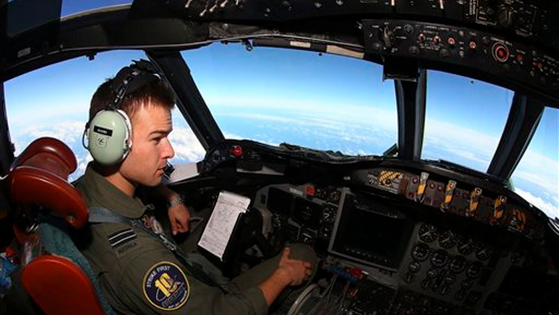 In this Wednesday, March 26, 2014 photo, Flight Lt. Russell Adams looks out from the cockpit on board a Royal Australian Air Force AP-3C Orion, during a search for the missing Malaysia Airlines Flight 370 in the southern Indian Ocean. A French satellite scanning the Indian Ocean for remnants of the missing jetliner found a possible plane debris field containing 122 objects, a top Malaysian official said Wednesday, calling it "the most credible lead that we have." (AP Photo/Paul Kane, Pool)