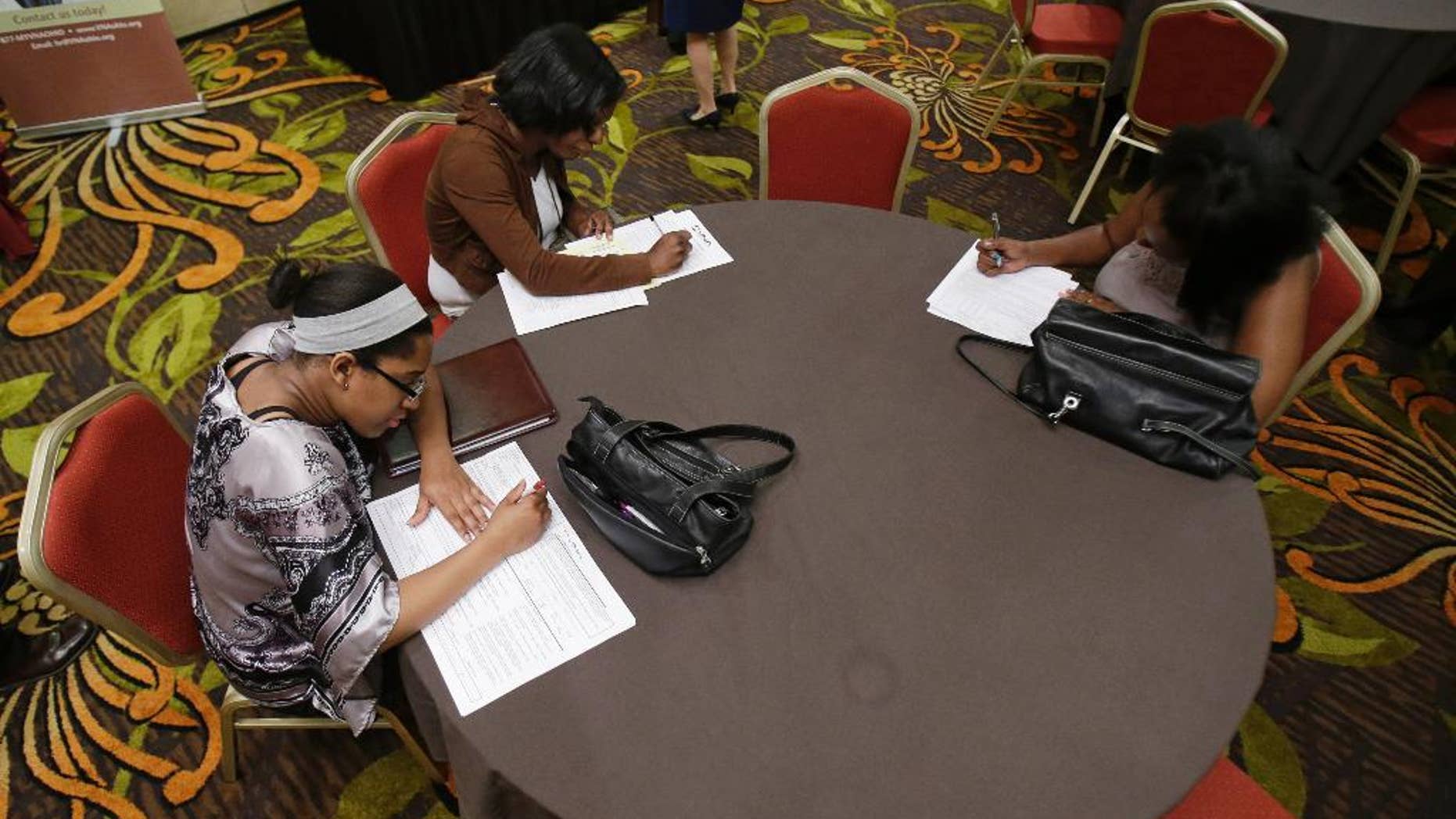 In this Thursday, June 12, 2014 photo, Desirae Gooch, left, fills out an application for a nurse's assistant job, alongside other job seekers filling out applications at the Cleveland Career Fair in Independence, Ohio. The Labor Department issues its May report on job openings and labor turnover on Tuesday, July 8, 2014. (AP Photo/Tony Dejak)
