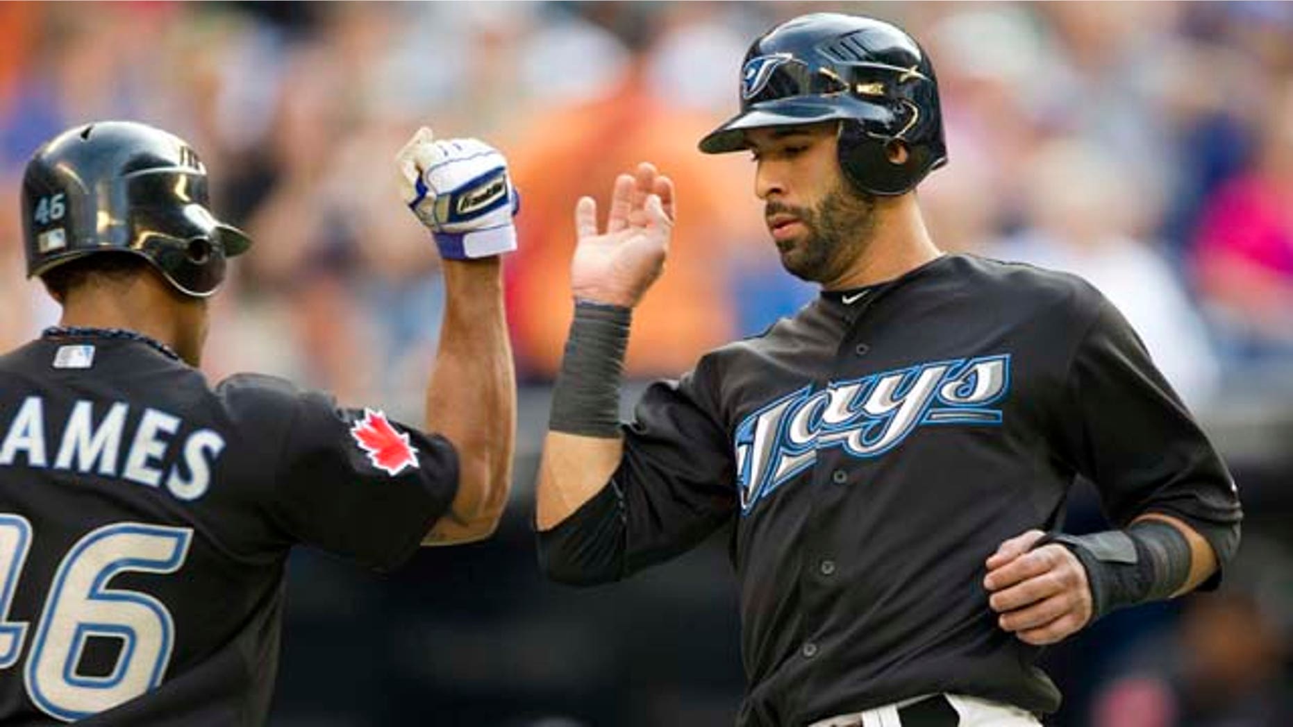 Toronto Blue Jays' Jose Bautista, right, is congratulated by Eric Thames after scoring against the New York Yankees during the first inning of a baseball game in Toronto on Thursday, July 14, 2011. (AP Photo/The Canadian Press, Frank Gunn)