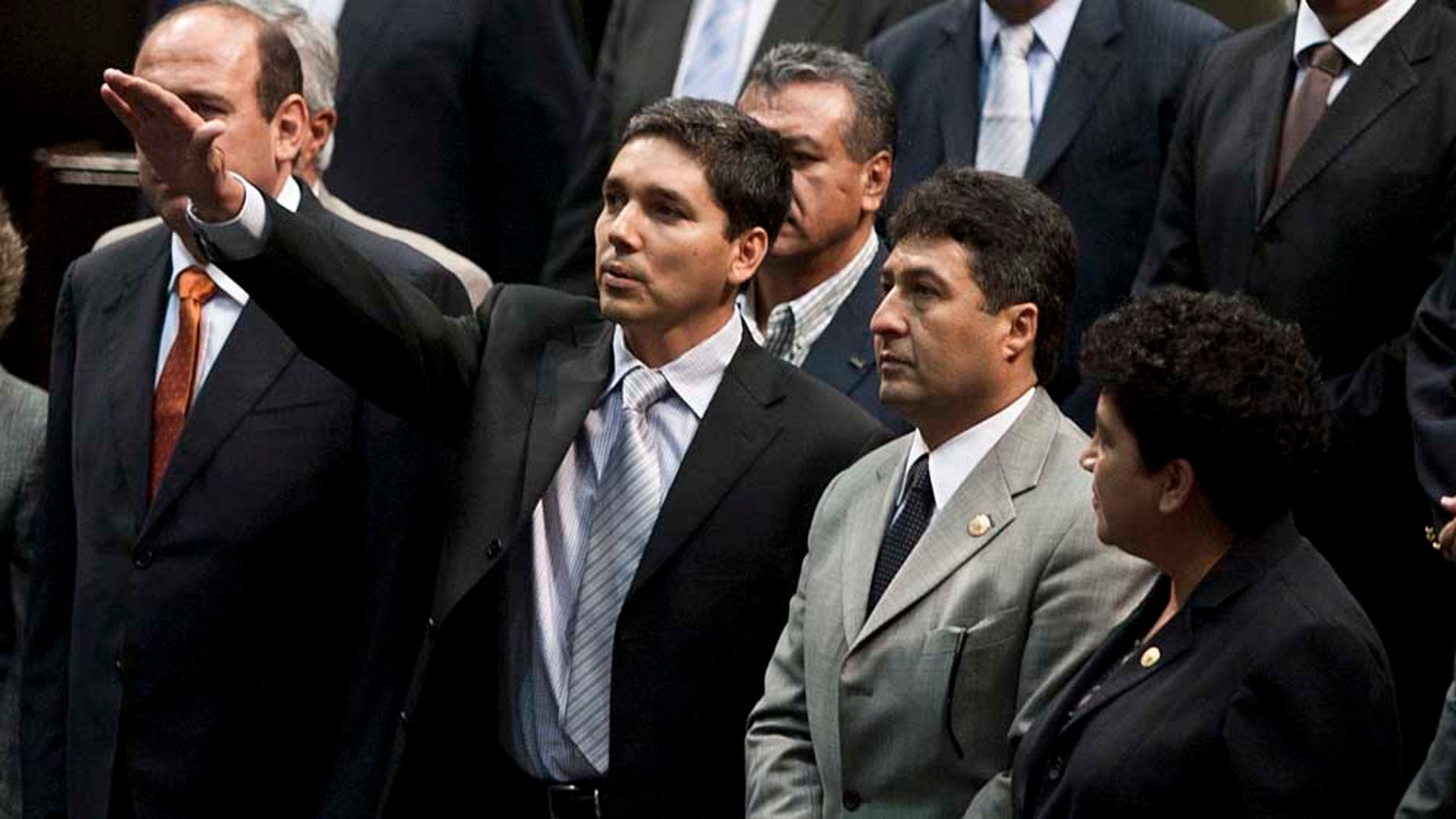 Julio Cesar Godoy Toscano, center, raises his hand as he is sworn in as federal congressman at the National Congress in Mexico City, Thursday Sept. 23, 2010. Godoy, who is wanted by federal authorities for alleged links to drug cartels, evaded a police operation to try to prevent him from being sworn in and gain congressional immunity. (AP Photo/Fernando Castillo)