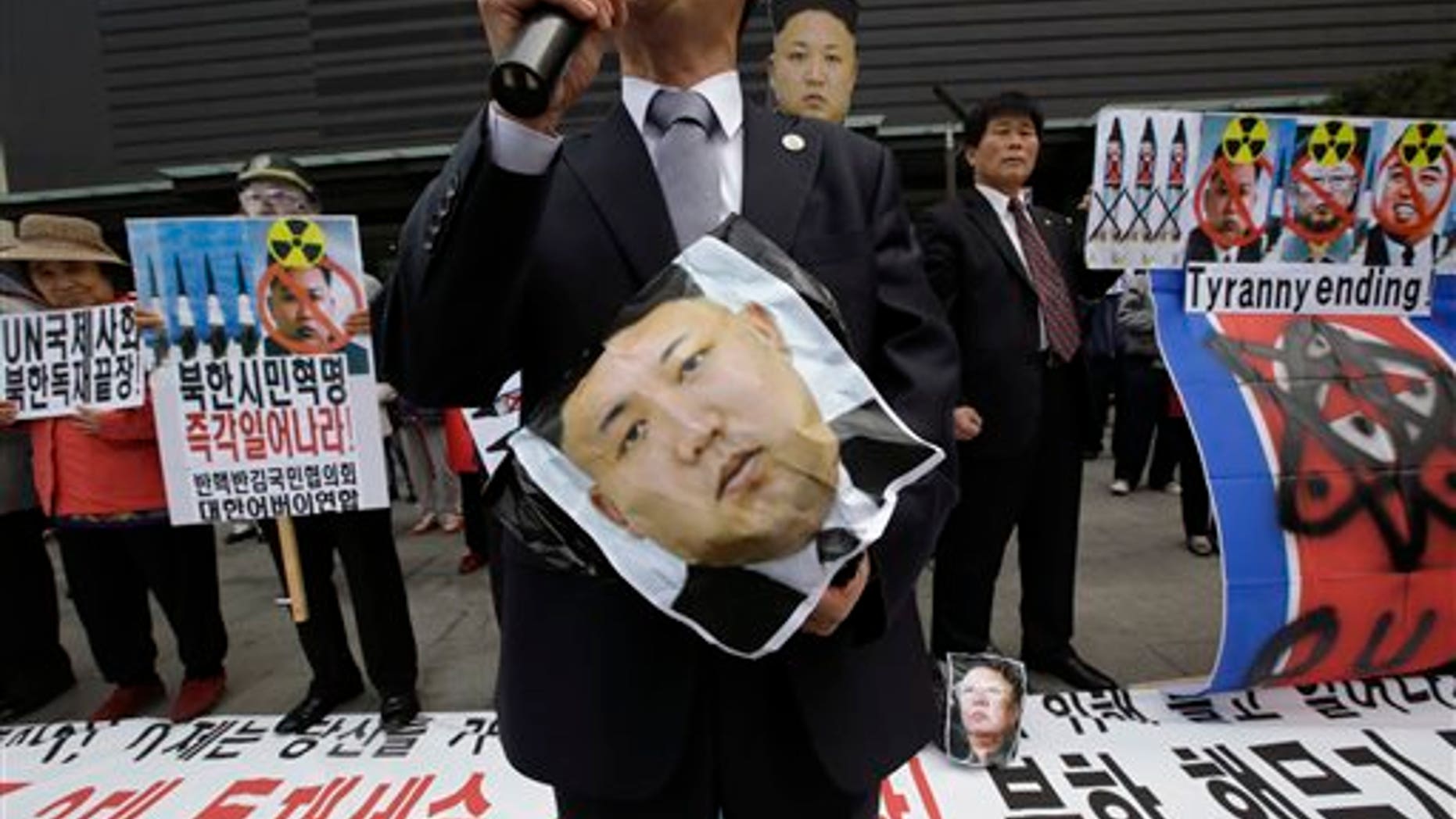 South Korean protesters hold a picture of North Korean leader Kim Jong Un during an anti-North Korea rally against recent missile launches and provocative acts, on the birthday of its founder, Kim Il Sung, in Seoul, South Korea, Tuesday, April 15, 2014. The banners read: "Denounce North Korea's dictatorship." (AP Photo/Lee Jin-man)