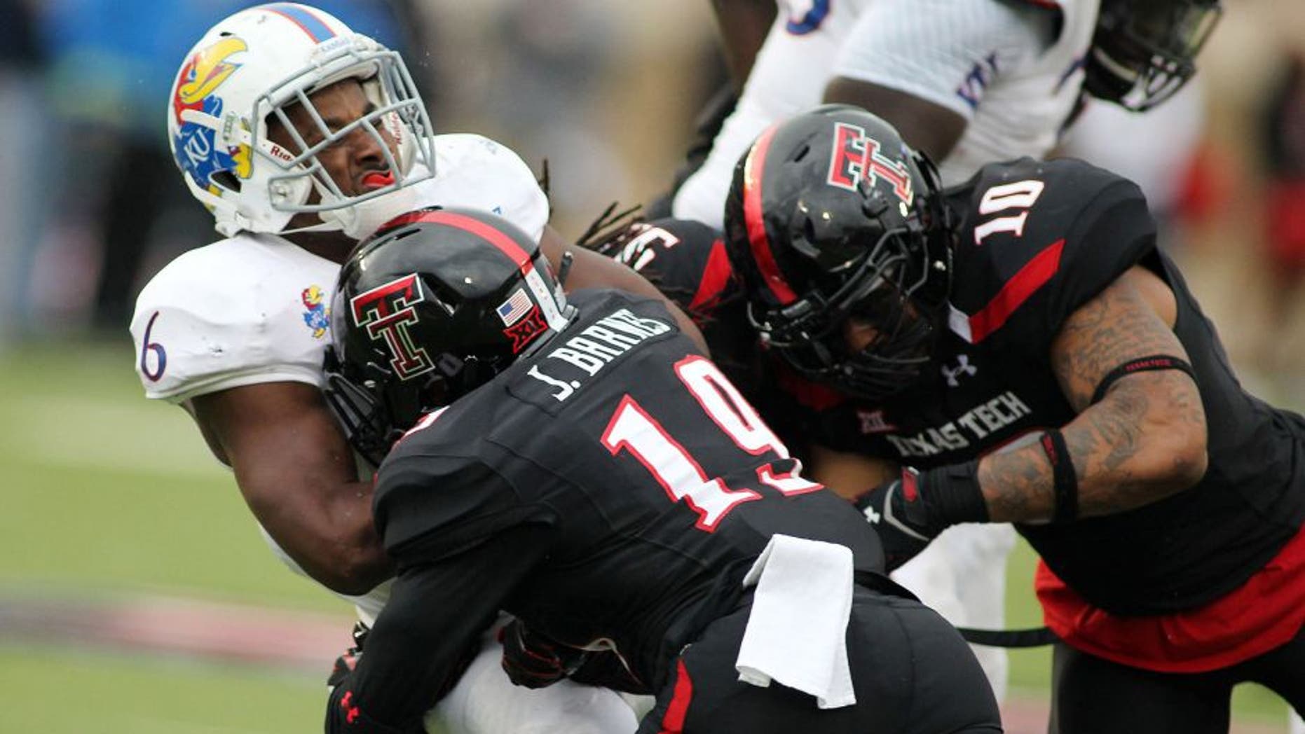 Oct 18, 2014; Lubbock, TX, USA; Kansas Jayhawks running back Corey Avery (6) is stopped by Texas Tech Red Raiders defensive back Pete Robertson (10) and safety Jalen Barnes )19) in the second half at Jones AT&T Stadium. Mandatory Credit: Michael C. Johnson-USA TODAY Sports