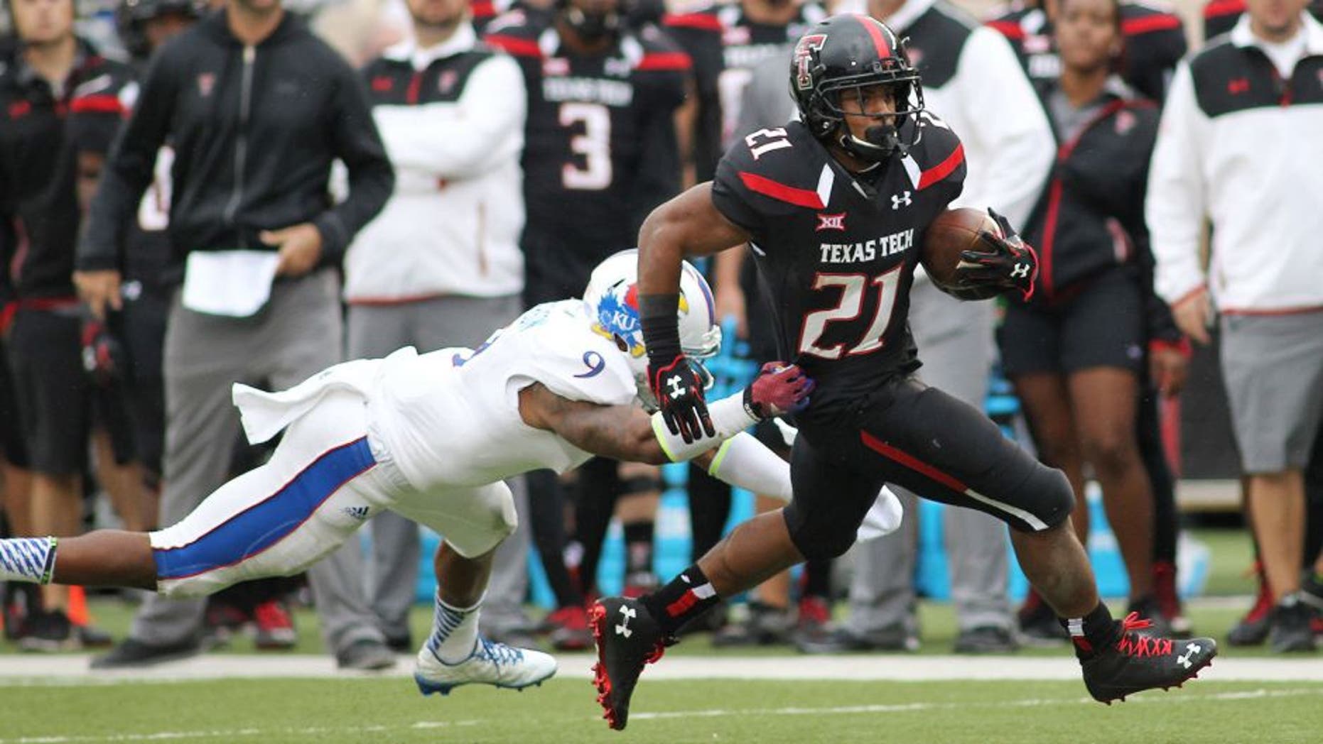 Oct 18, 2014; Lubbock, TX, USA; Kansas Jayhawks safety Fish Smithson (9) attempts to tackle Texas Tech Red Raiders running back DeAndre Washington (21) in the second half at Jones AT&T Stadium. Mandatory Credit: Michael C. Johnson-USA TODAY Sports
