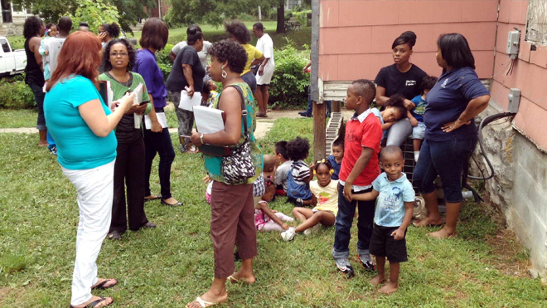 July 30, 2013: Dena Washington, middle of 3 women on left, director of the Christian Academy Child Care, stands behind a house near the center with children waiting to be picked up after a car crashed into the day care in Kansas City, Mo.