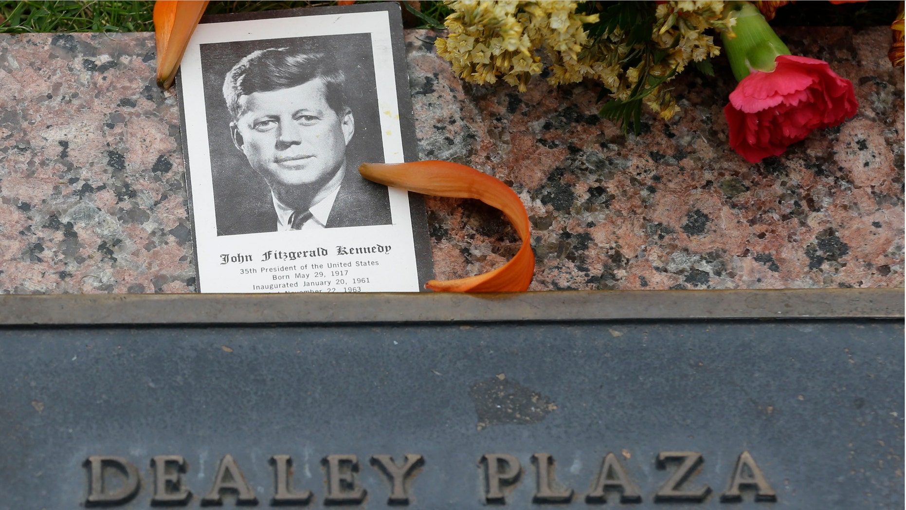 A photo of JKF and flowers lay on a plaque at Dealey Plaza in Dallas, Thursday, Nov. 21, 2013. Loose gatherings of the curious and conspiracy-minded at Dallasâ Dealey Plaza have marked past anniversaries of the assassination of President John F. Kennedy. But for the 50th anniversary, the city of Dallas has planned a solemn ceremony Friday in the plaza he was passing through when shots rang out. There will be brief remarks by the mayor and the tolling of church bells. (AP Photo/LM Otero)