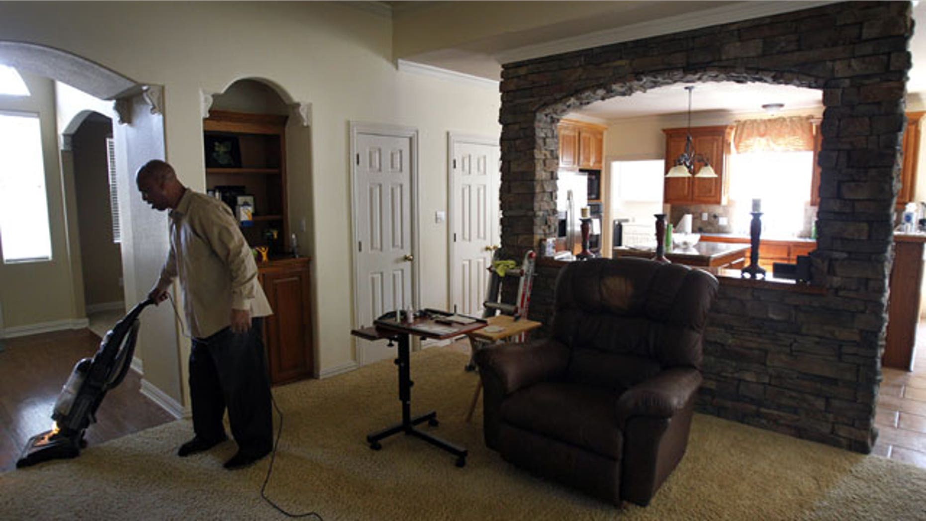 In this photo taken Wednesday, July 27, 2011, Kenneth Robinson vacuums the spacious living room of the home in Flower Mound, Texas.