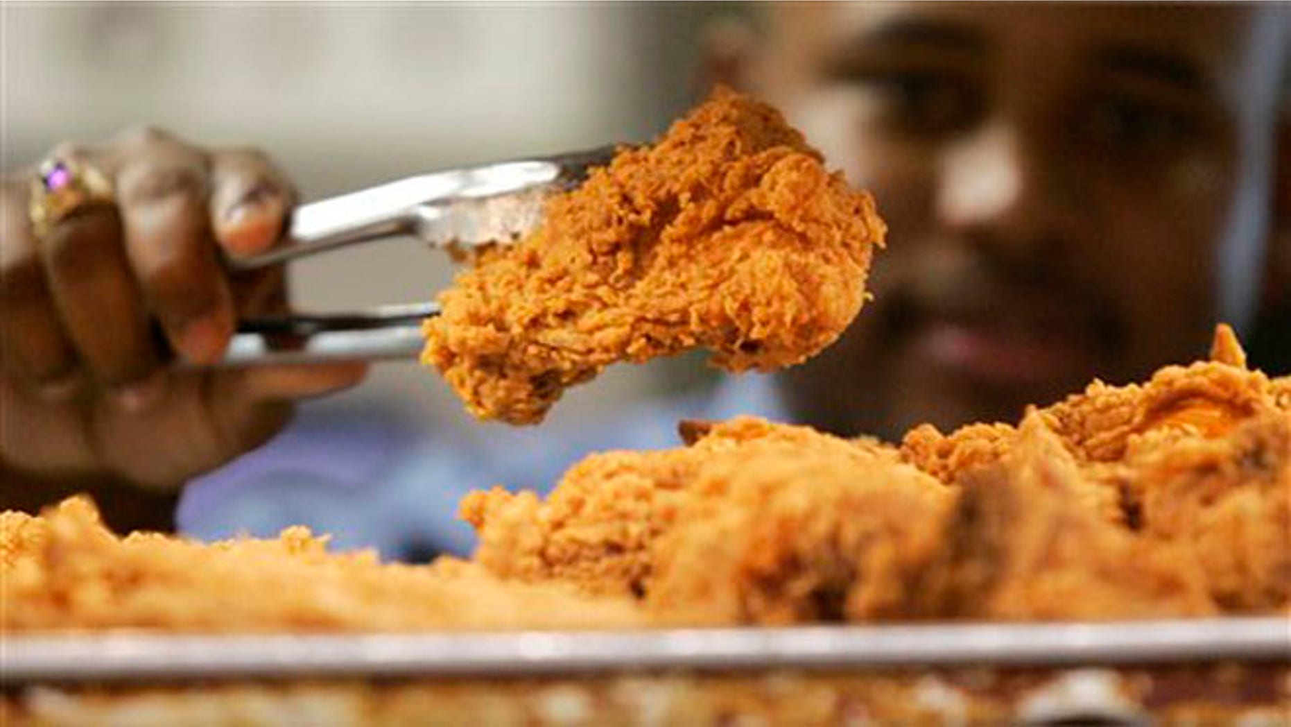 FILE - A Kentucky Fried Chicken employee uses tongs to hold up an sample of the company's trans fat-free Extra Crispy fried chicken in New York.