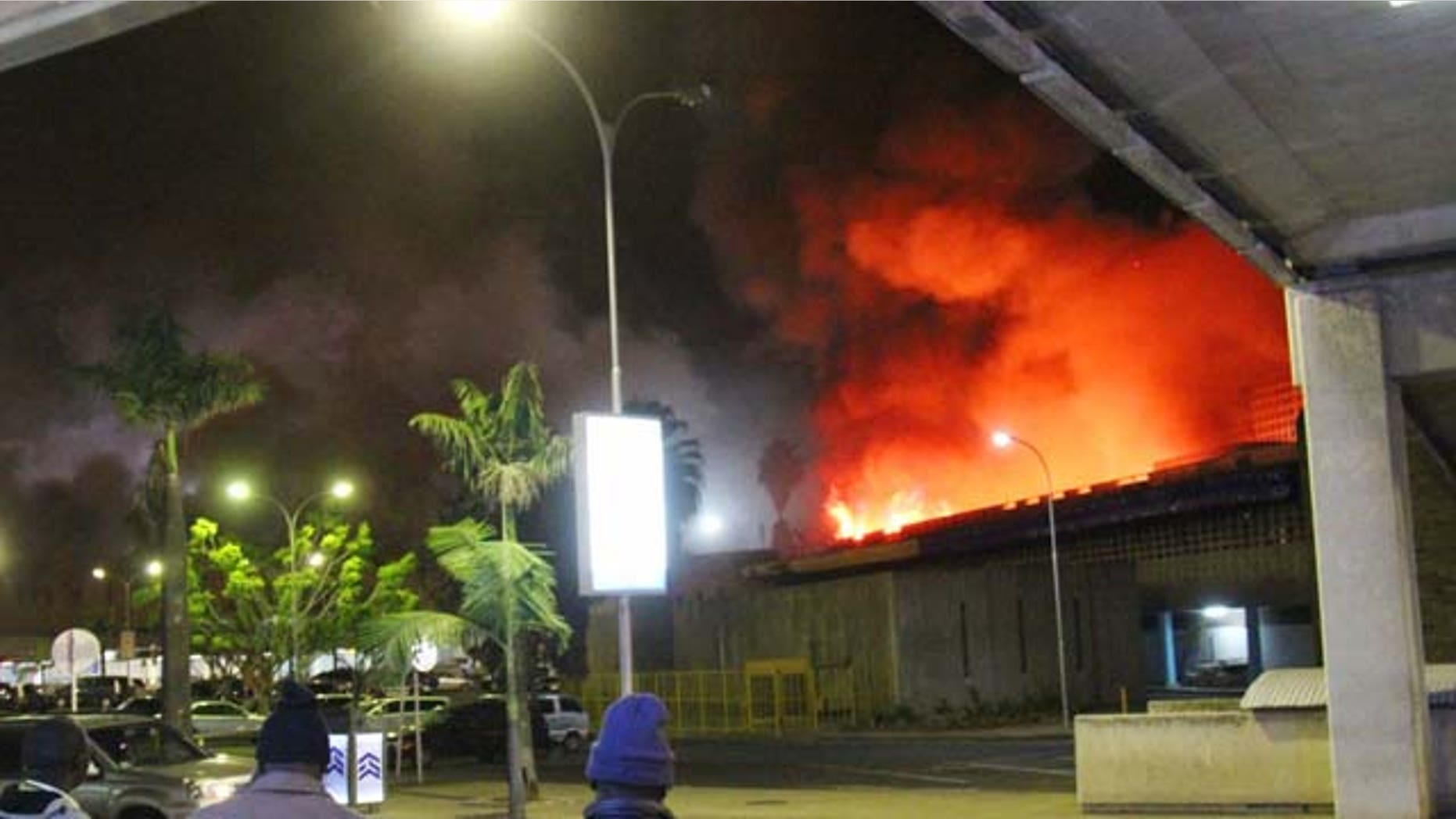 August 7, 2013: People watch a large blaze raging at the Jomo Kenyatta International Airport in Nairobi, Kenya early Tuesday. (AP Photo/Kyodo News)