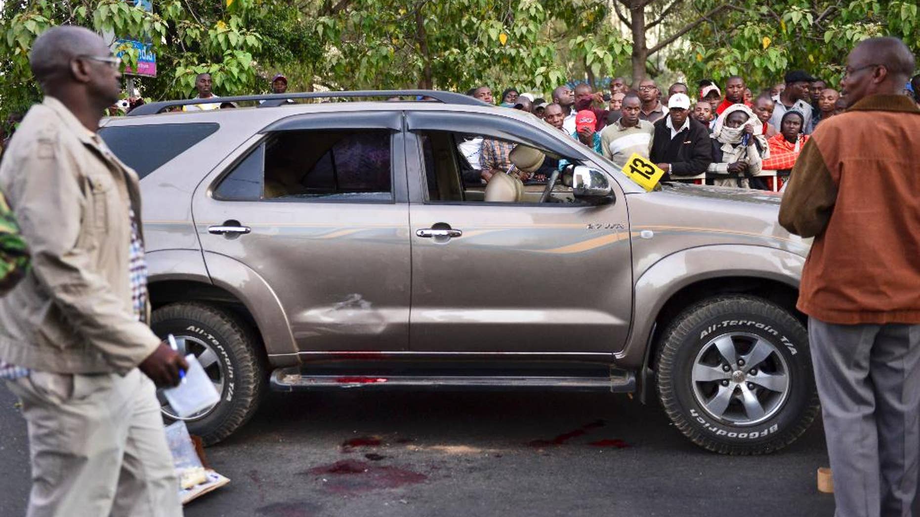Onlookers gather at the scene after a Kenyan lawmaker was shot dead by gunmen on a main street in Nairobi, Kenya Saturday, Feb. 7, 2015. Masked gunmen shot and killed Kenyan lawmaker George Muchai early Saturday, a senior police official said, alongside his two bodyguards and a driver after they stopped to buy a newspaper from a vendor on Nairobi's main street. (AP Photo)