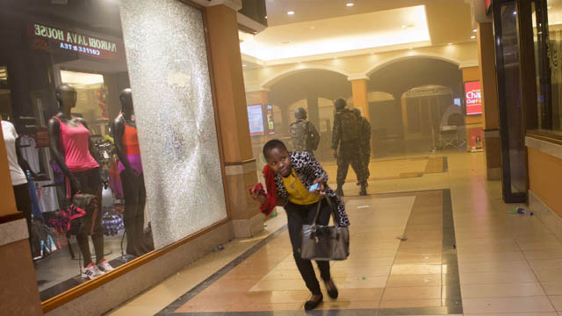 FILE - In this Saturday, Sept. 21, 2013 file photo, a woman who had been hiding during the gun battle runs for cover after armed police enter the Westgate Mall in Nairobi, Kenya, after gunmen threw grenades and opened fire at the upscale mall. (AP Photo)