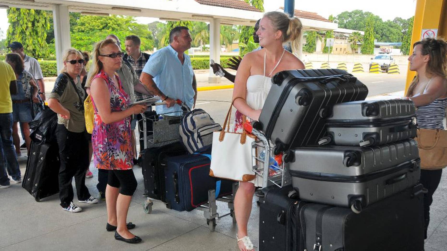 British tourists queue with their luggage to leave by charter flight from the international airport in Mombasa, Kenya Friday, May 16, 2014. Britain's government warned its citizens this week to avoid the coastal city of Mombasa and beach towns nearby, prompting a travel company to cut short the vacations of hundreds of British citizens and fly them home, while Kenya's National Disaster Operation Centre says that two explosions in Nairobi have killed at least four people Friday with one blast targeting a mini-van that Kenyans use for public transportation and a second blast went off in a market. (AP Photo)