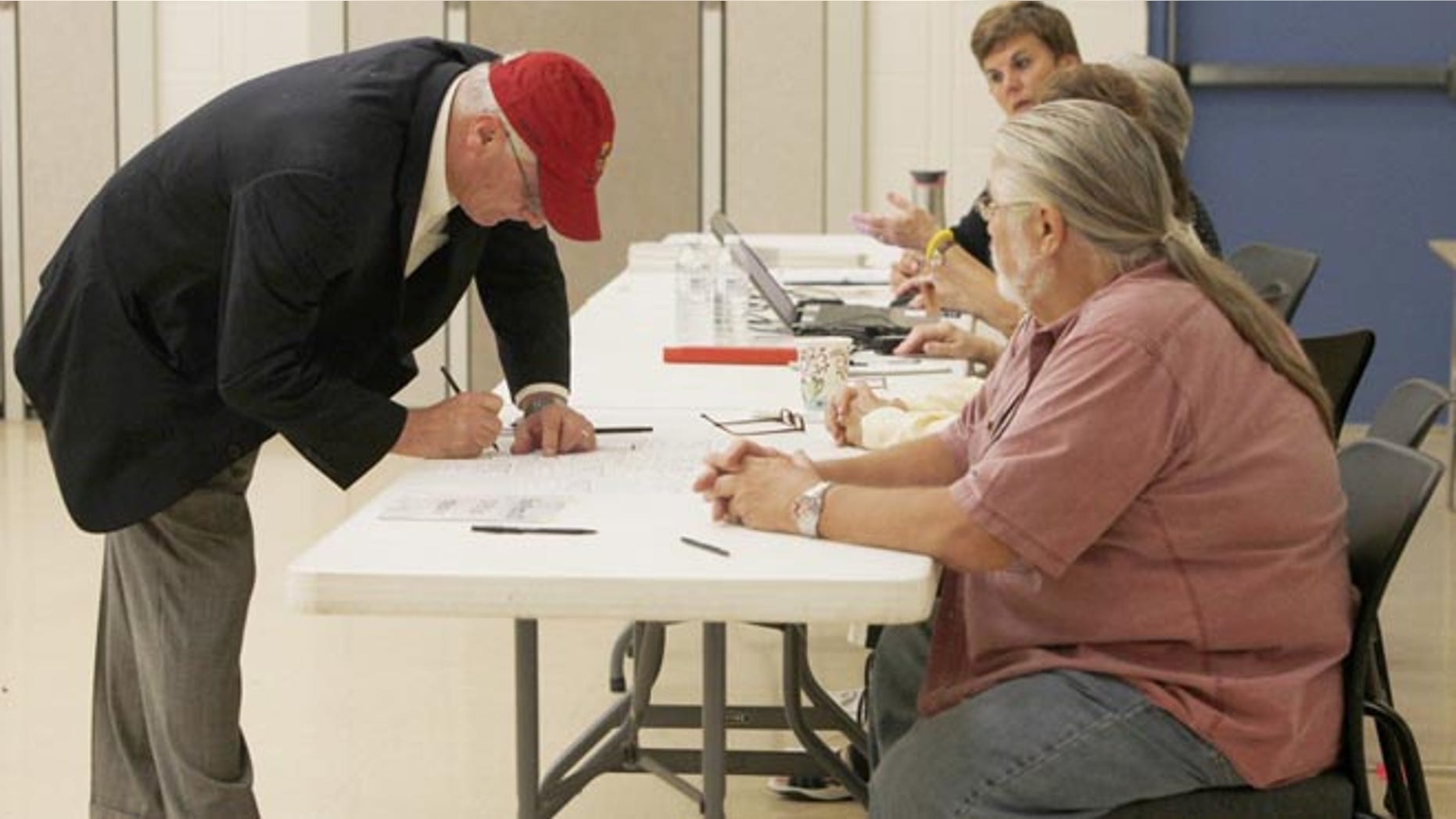 Aug. 5, 2014: Rep. Kerry Bentivolio signs in to vote at Johnson Elementary School in Milford, Mich.