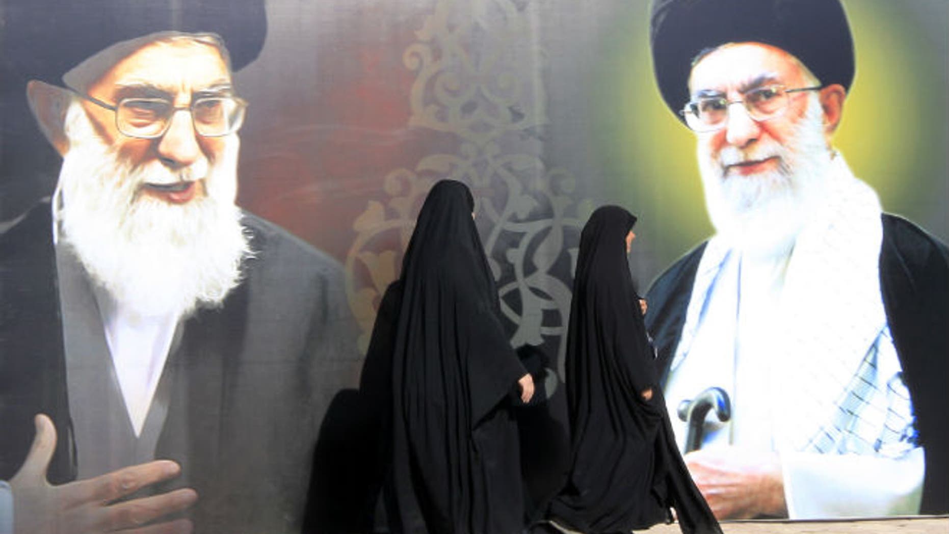 Iraqi women walk past a poster depicting images of Shi'ite Iran's Supreme Leader Ayatollah Ali Khamenei at al-Firdous Square in Baghdad February 12, 2014. (REUTERS/Ahmed Saad)