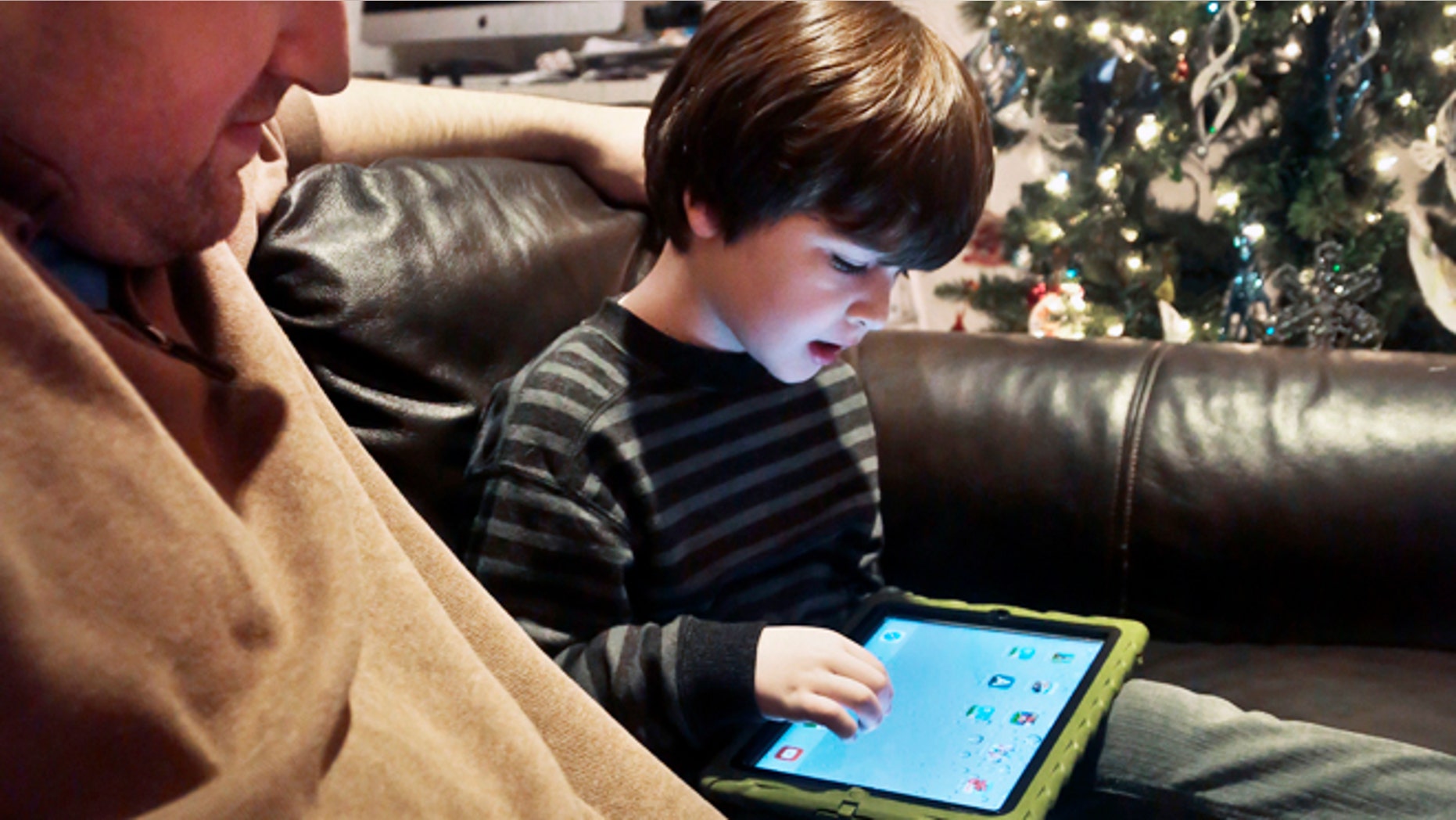 Dec. 3, 2013: Adam Cohen watches as his son Marc, 5, uses a tablet at their home in New York. Tablets of all types are expected to rank among the top holiday gifts for children this year, but some experts and advocates question the educational or developmental benefits for youngsters.