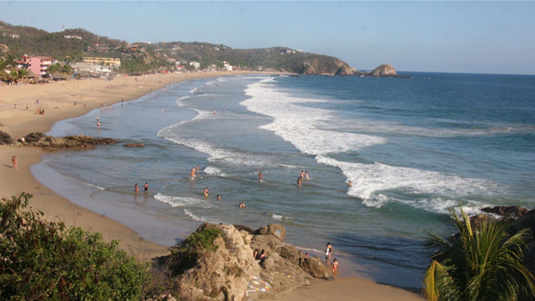 This Jan. 6, 2013 photo shows visitors bathing in the surf along the beach in Zipolite, Mexico. A sleepy town with one main street and no ATMs, Zipolite is one many tiny coastal pueblos that dot the Pacific in Mexico's Southern state of Oaxaca. (AP Photo/Jody Kurash)