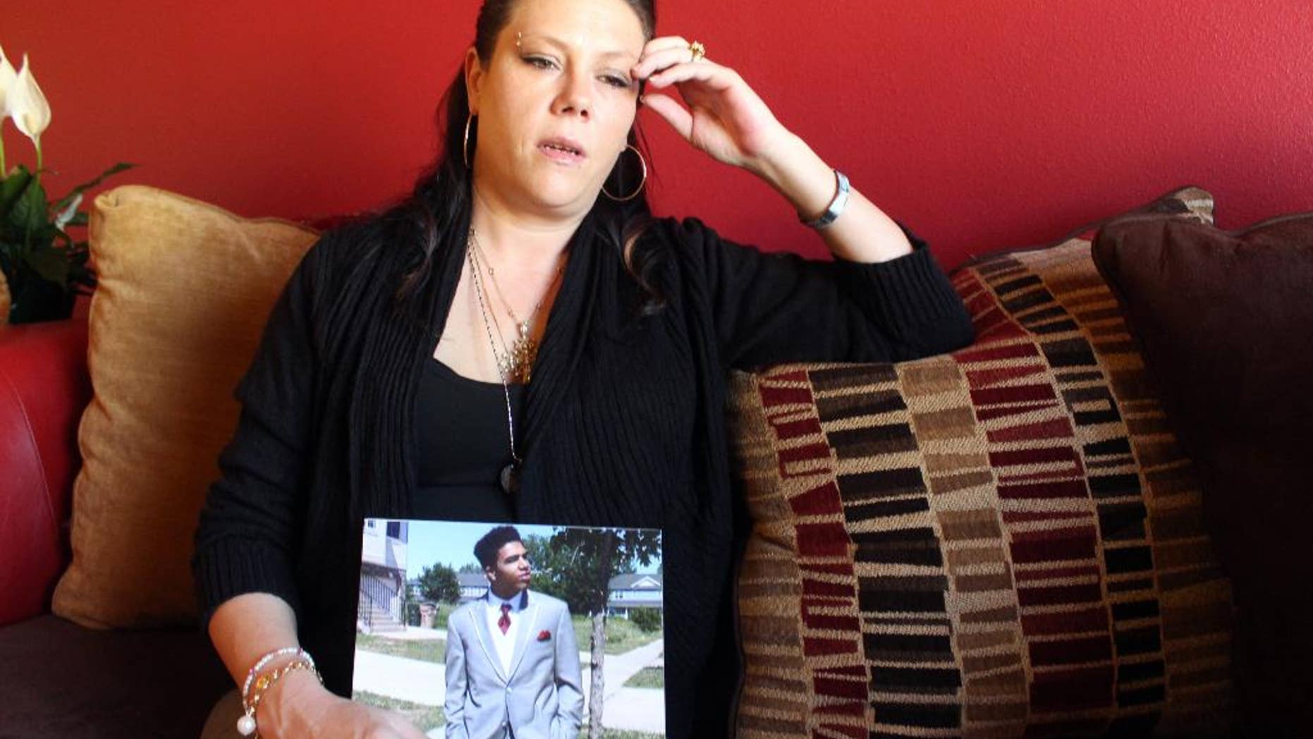 Andrea Irwin holds a photo of her son Tony Robinson Tuesday, April 1, 2015 in Madison, Wis. Irwin, whose biracial son died at the hands of a white Madison Wisconsin police officer in March, says she trusts prosecutors will get to the truth of what really happened. (AP Photo/Carrie Antlfinger)
