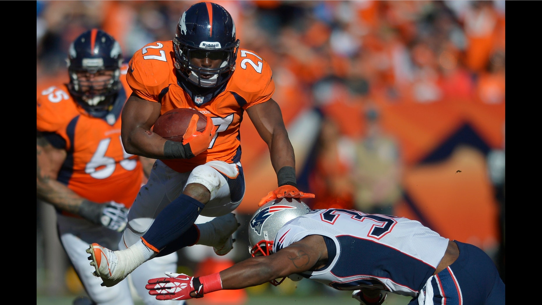 Denver Broncos running back Knowshon Moreno (27) leaps over New England Patriots strong safety Duron Harmon (30) during the first half of the AFC Championship NFL playoff football game in Denver, Sunday, Jan. 19, 2014. (AP Photo/Jack Dempsey)
