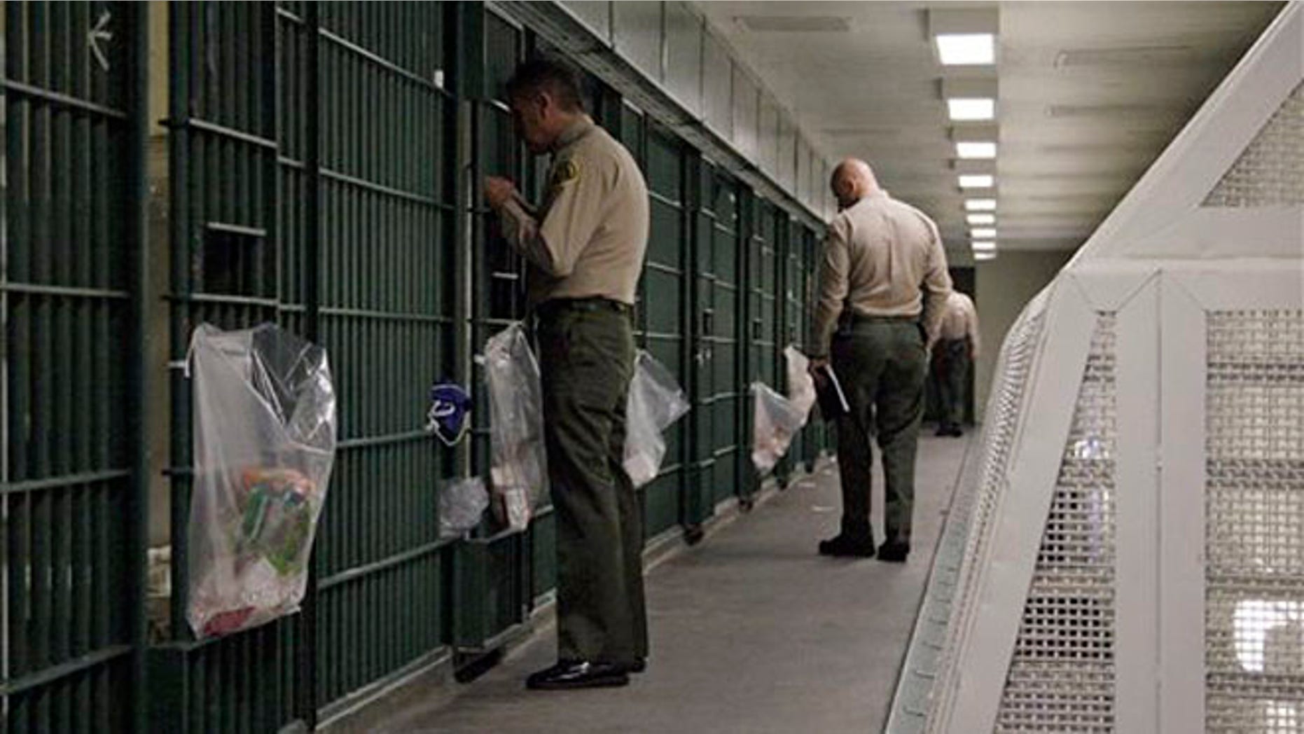 FILE - In this Oct. 3, 2012, file photo, Los Angeles County Sheriff's deputies inspect a cell block at the Men's Central Jail in downtown Los Angeles. A new federal civil rights indictment alleges that two Los Angeles County sheriff's deputies beat a handcuffed prisoner at the Men's Central Jail. The four-count indictment returned by a grand jury late Thursday Feb. 6, 2014, follows earlier indictments of 18 current and former Los Angeles County deputies on corruption and civil rights offenses. (AP Photo/Reed Saxon, File)