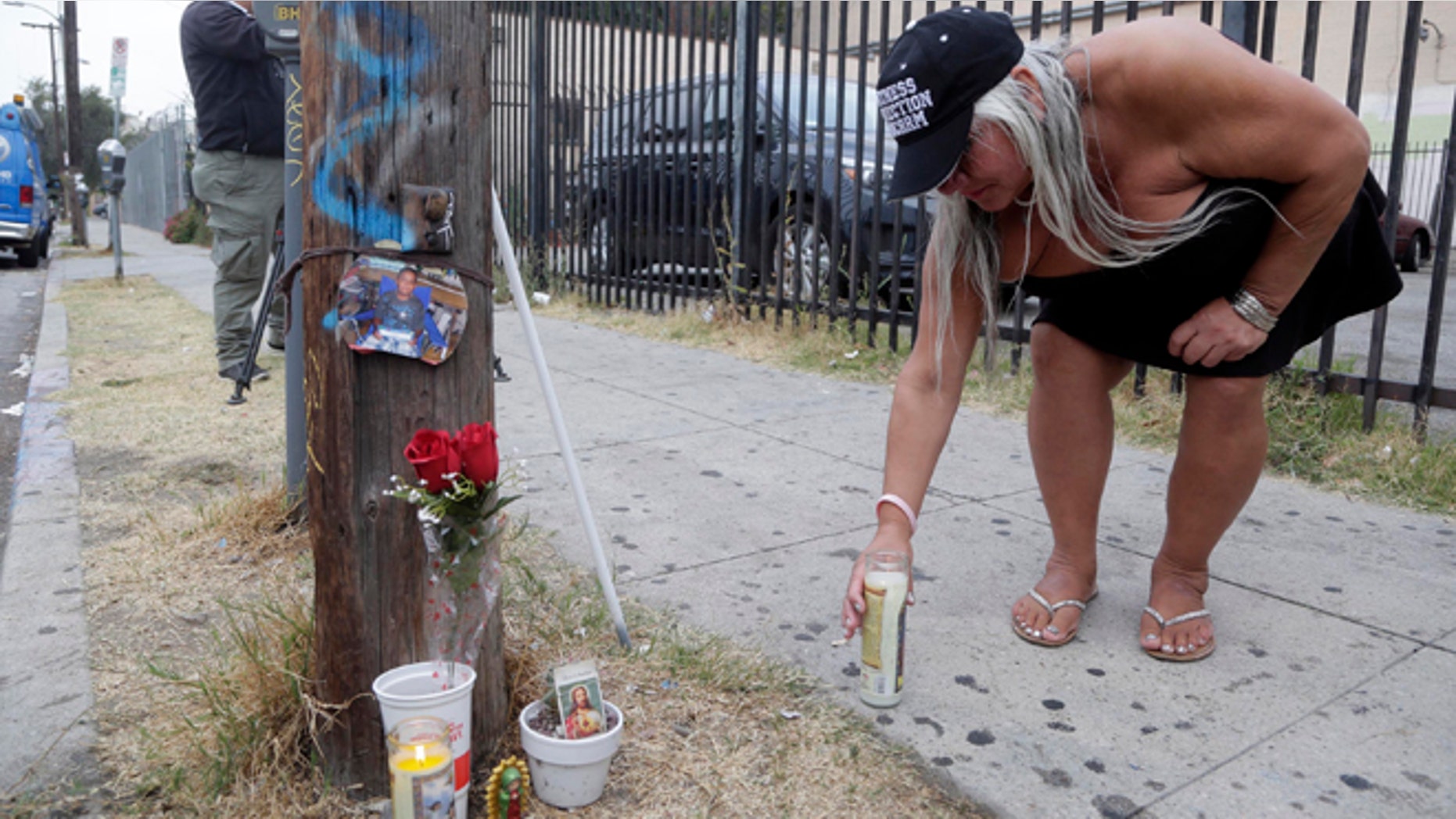 Maria Ramirez places a candle near a police involved shooting of a teen in Los Angeles on Wednesday, Aug. 10, 2016.
