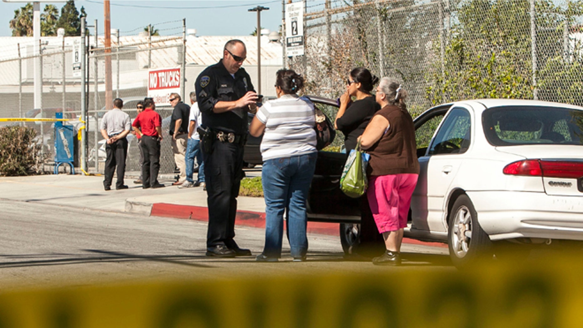 Oct. 24, 2012: Police investigators talk to people across the street from a family-owned business, United States Fire Protection Services, in Downey, Calif.