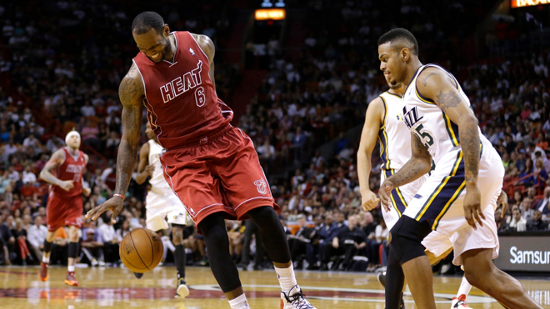 Miami Heat's LeBron James (6) reacts as he injures his left ankle while dribbling the ball towards the basket as Utah Jazz's Brandon Rush (25) defends in the third quarter of an NBA basketball game, Monday, Dec. 16, 2013, in Miami. James left the game but returned in the fourth quarter. The Heat defeated the Jazz 117-94. (AP Photo/Lynne Sladky)