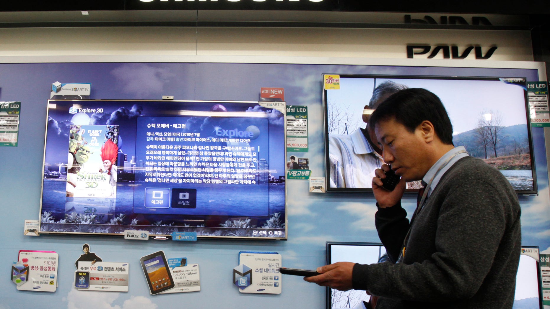 A salesman talks on his mobile phone as he walks past Samsung Electronics's LED television displays at an electronics store in Seoul.