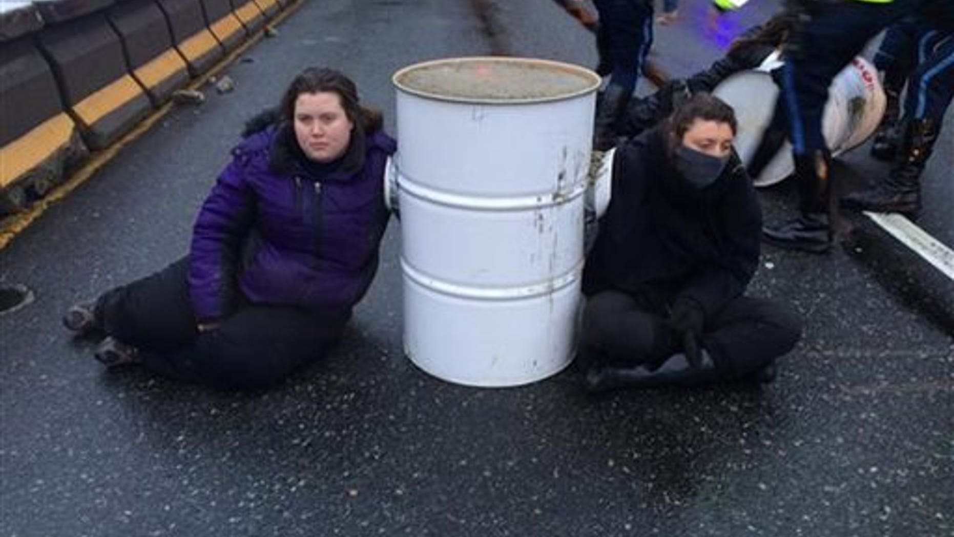 Protesters from the Boston contingent of Black Lives Matter sit near a barrel on Interstate 93 in Milton, Mass., on Jan. 15, 2015. (AP Photo/Massachusetts State Police)