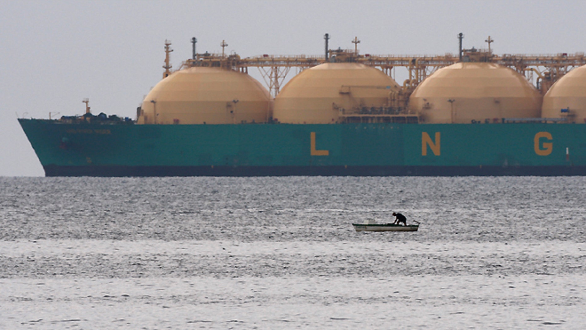 A fisherman stands in his boat as a liquid natural gas tanker (LNG) passes the coast near Havana on June 28, 2009. REUTERS/Desmond Boylan(CUBA ENERGY ENVIRONMENT) - RTR255FO