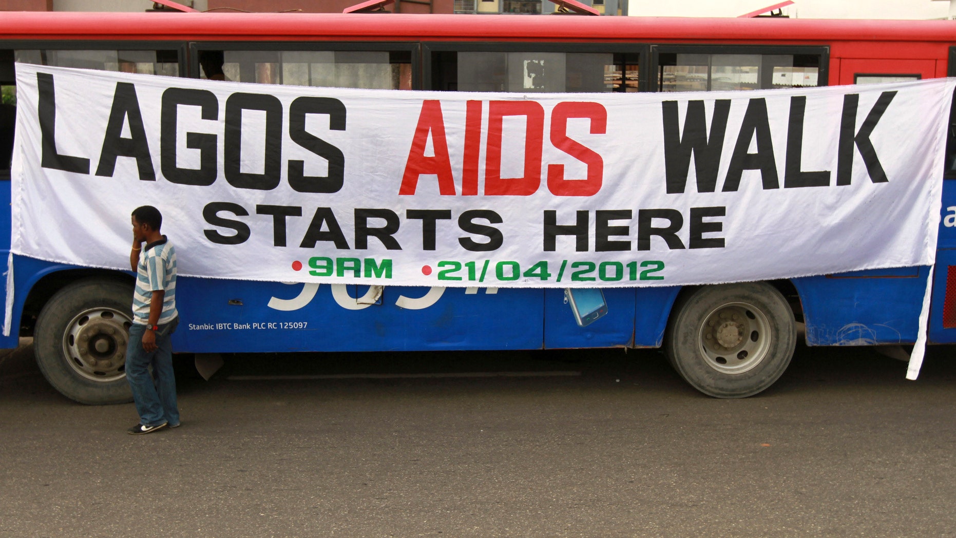 A man walks past a banner tied on a bus before the start of a charity walk on HIV/AIDS at the Ebute Mata district in Nigeria's commercial capital Lagos.